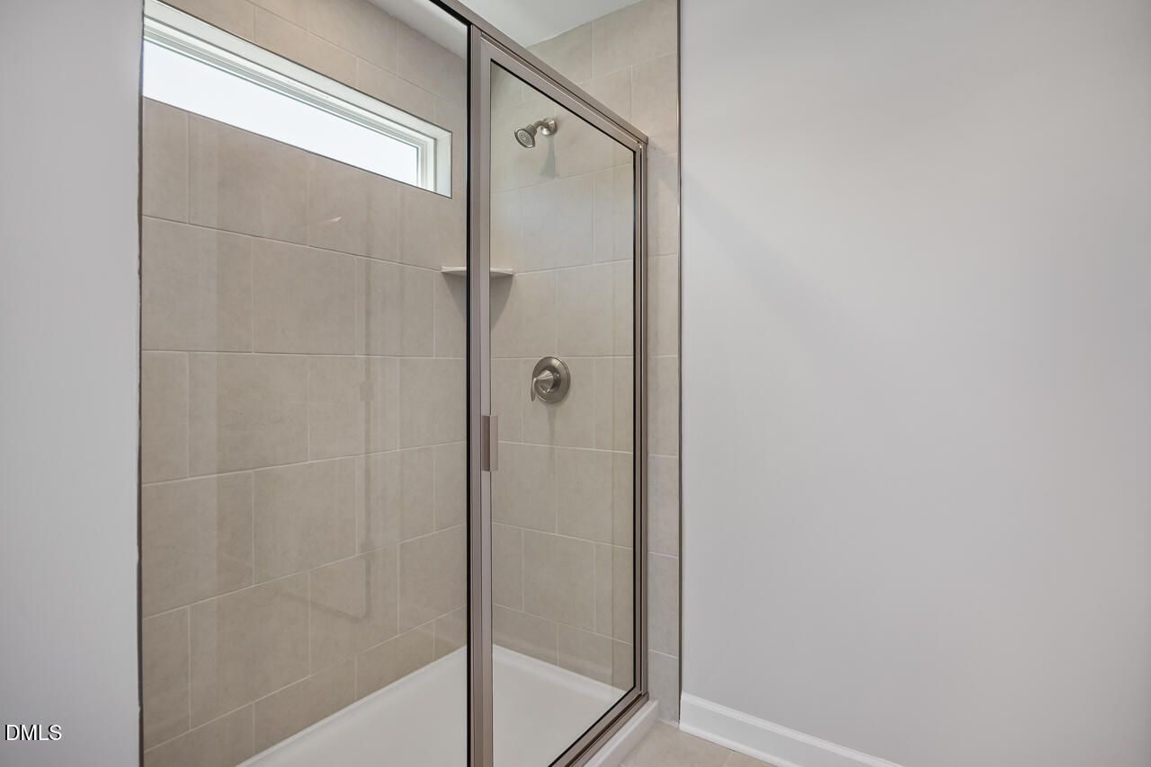 Modern walk-in shower with glass doors and tile surround in The Adalynn B floor plan, Gregory Village, Lillington, NC.