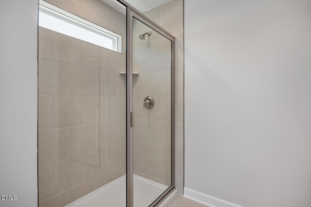 Modern walk-in shower with glass doors and tile surround in The Adalynn B floor plan, Gregory Village, Lillington, NC.