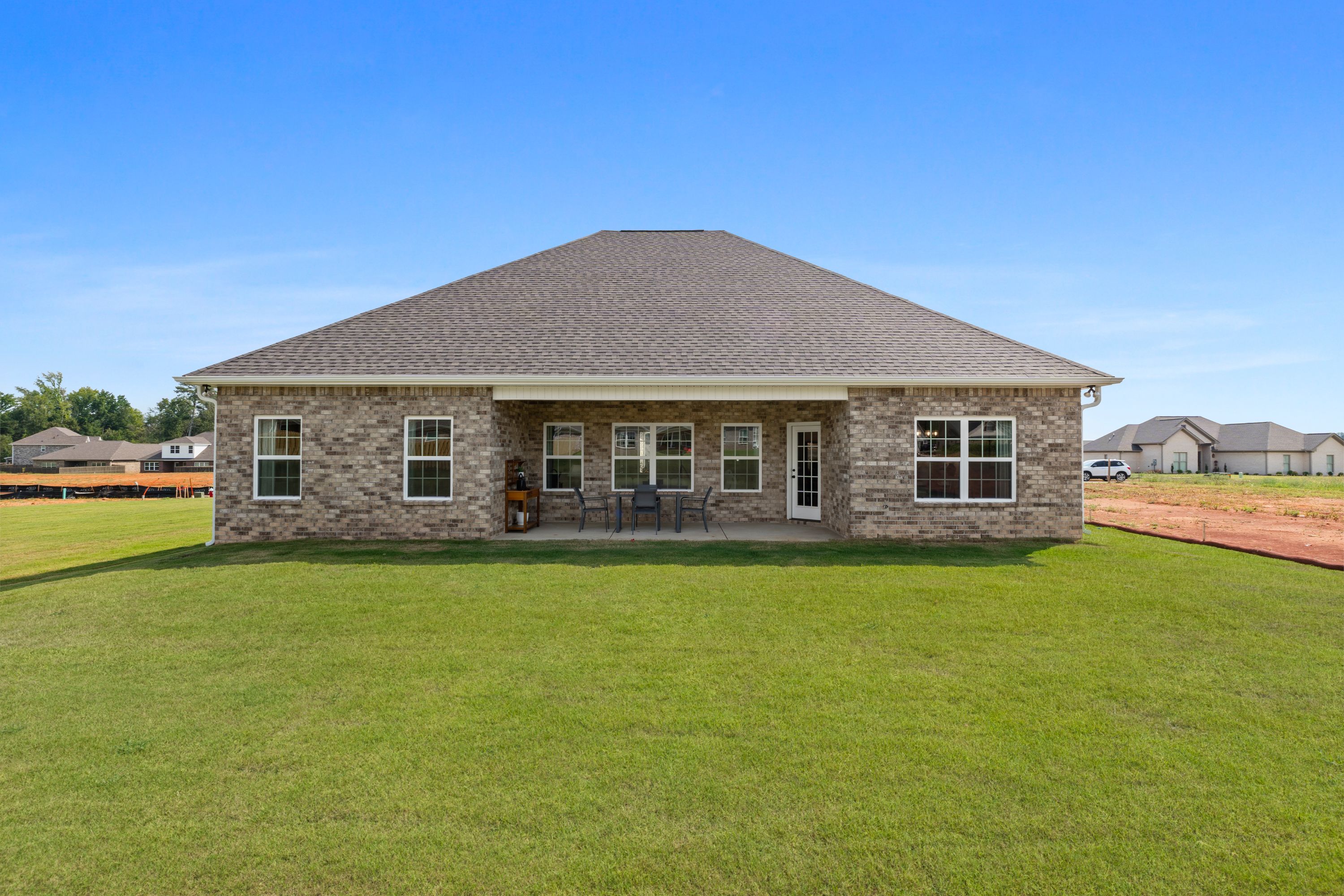 Rear view of brick home with covered patio and outdoor seating at River Road Estates in Decatur, Alabama