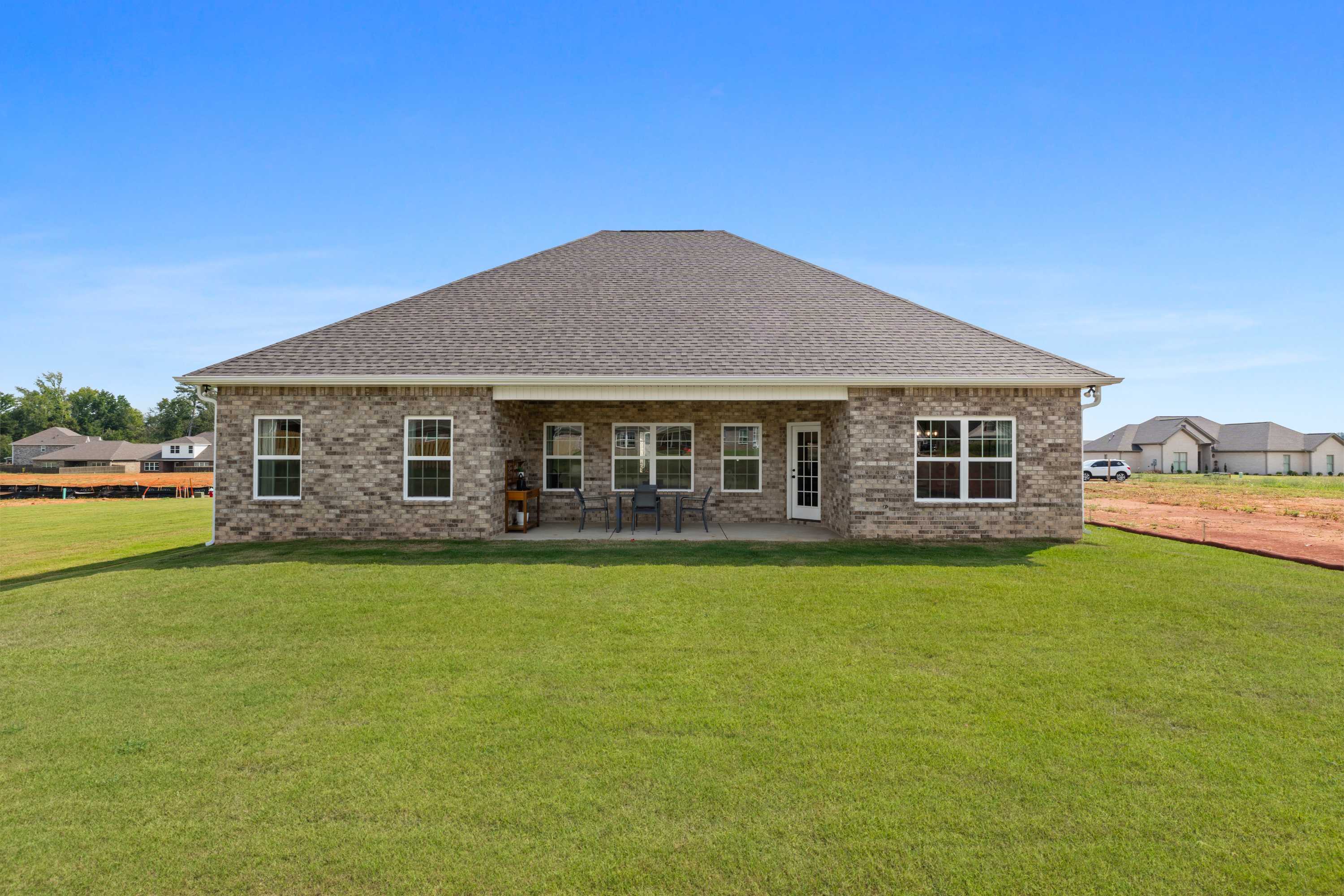 Rear view of brick home with covered patio and outdoor seating at River Road Estates in Decatur, Alabama