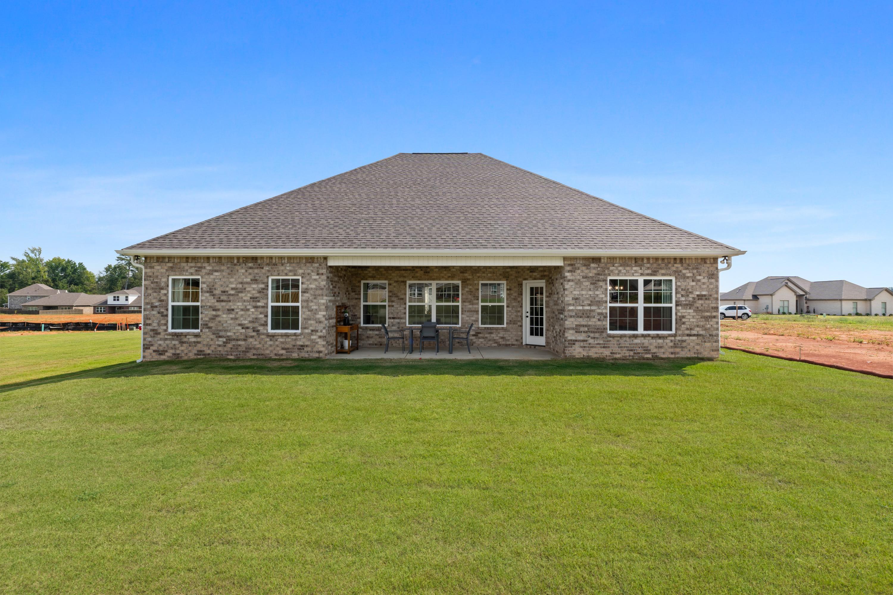 Rear view of brick home with covered patio and outdoor seating at River Road Estates in Decatur, Alabama