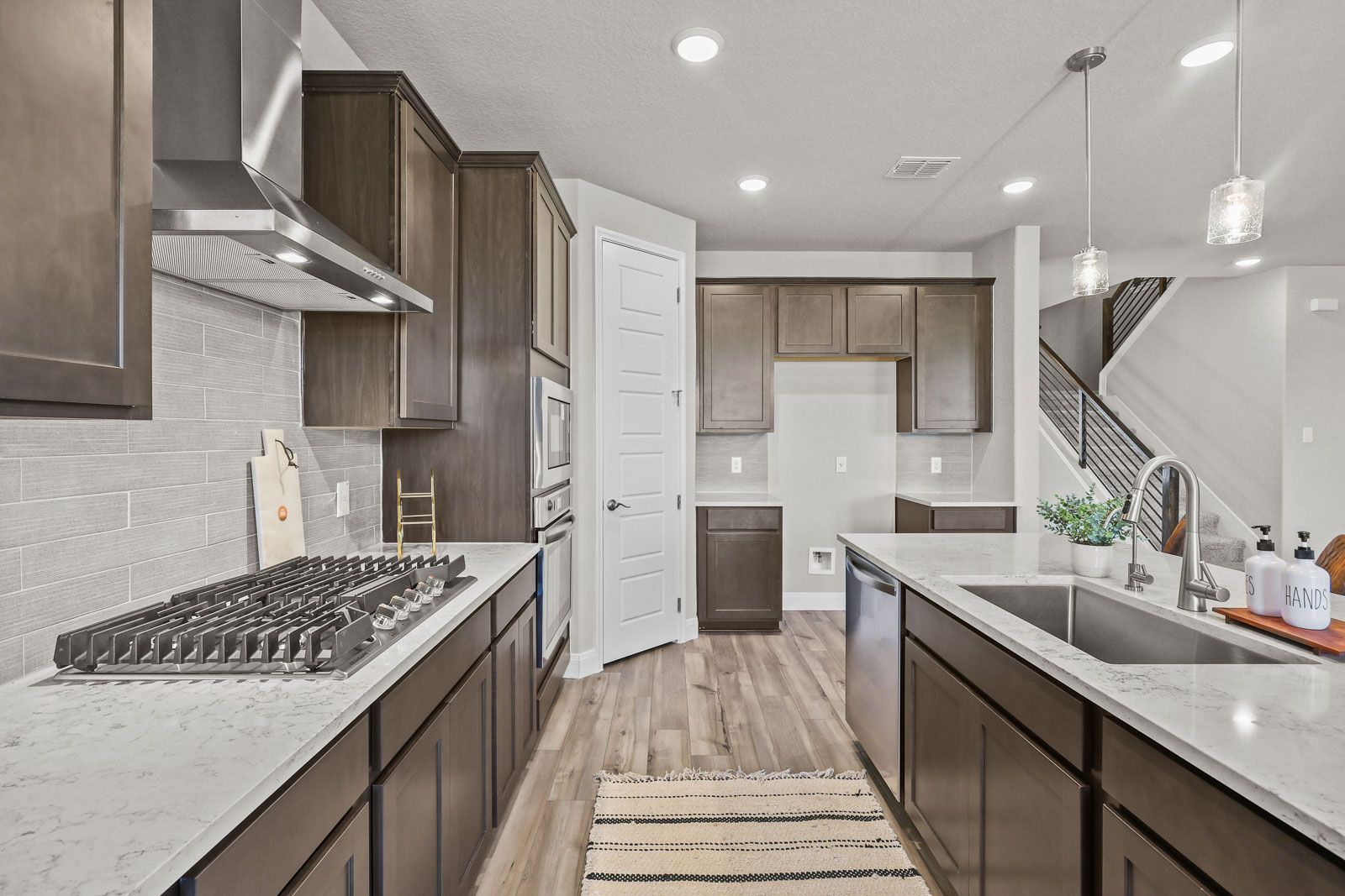 Modern kitchen in The Jennings G featuring dark wood cabinetry, quartz countertops, gas cooktop, and large center island.