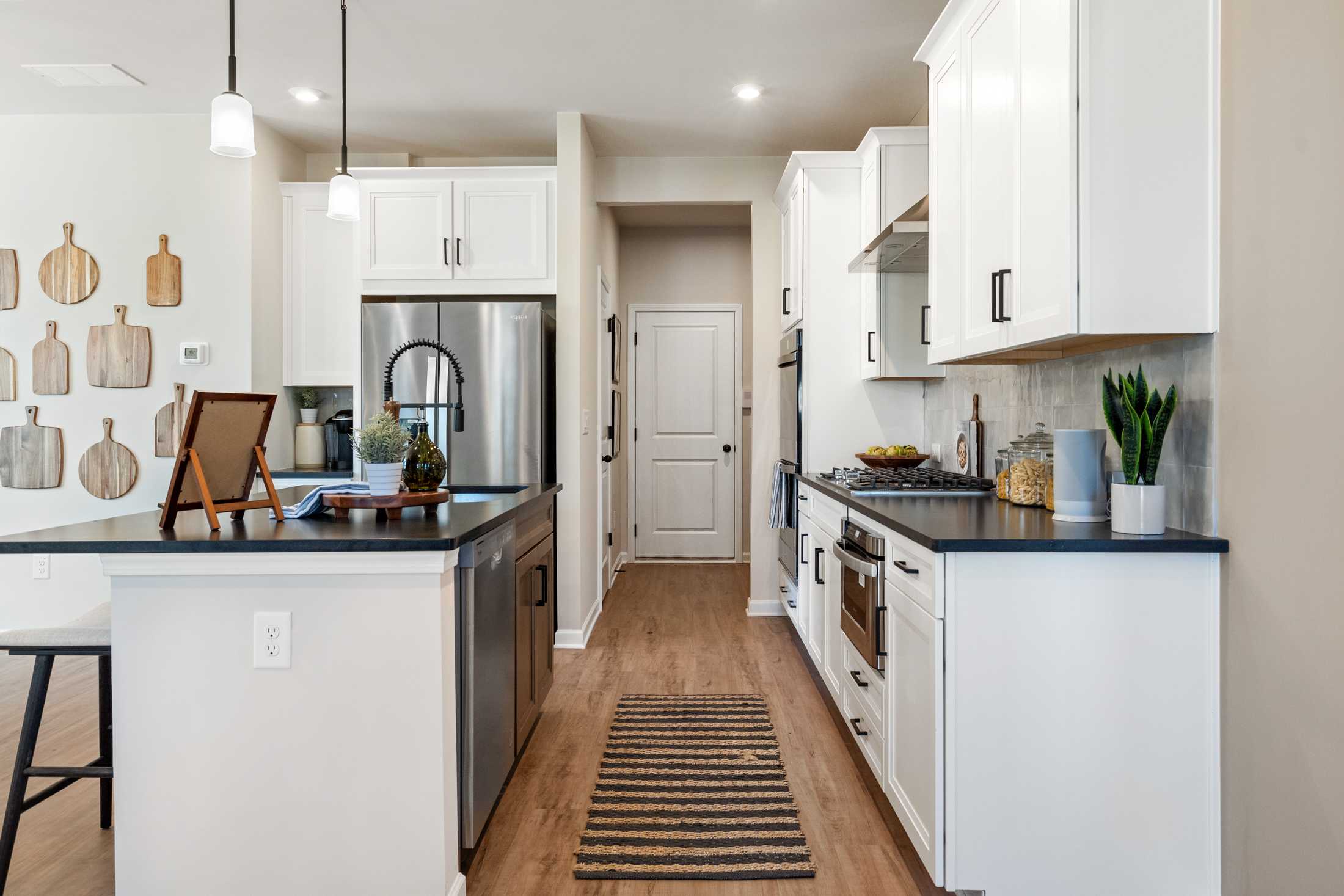 Spacious kitchen in The Marion B by Davidson Homes, white shaker cabinets, dark granite island, stainless steel appliances, hardwood floors