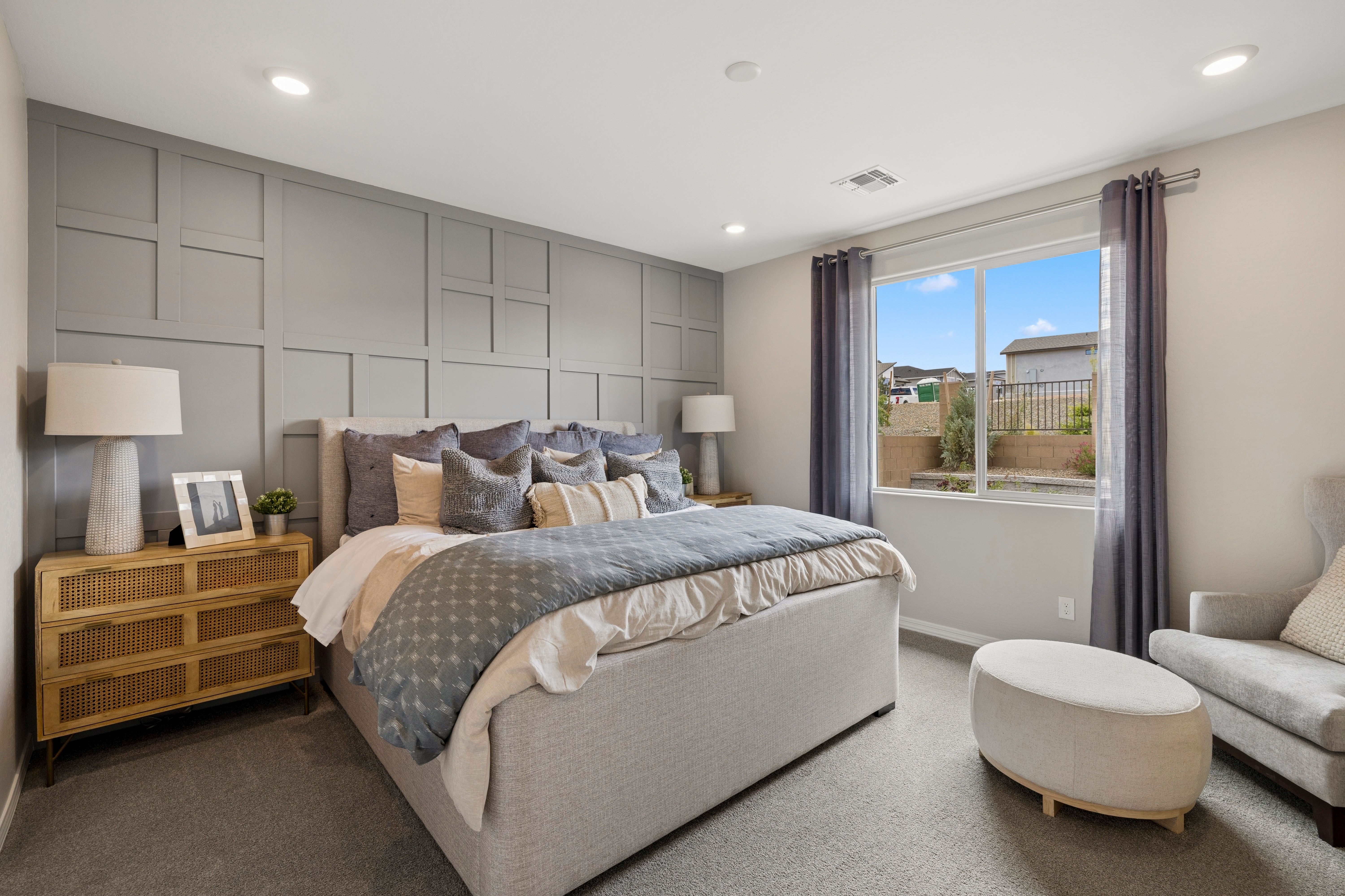 Elegant primary bedroom at South Ranch in Prescott AZ by Davidson Homes with gray shiplap wall, plush king bed, and window view