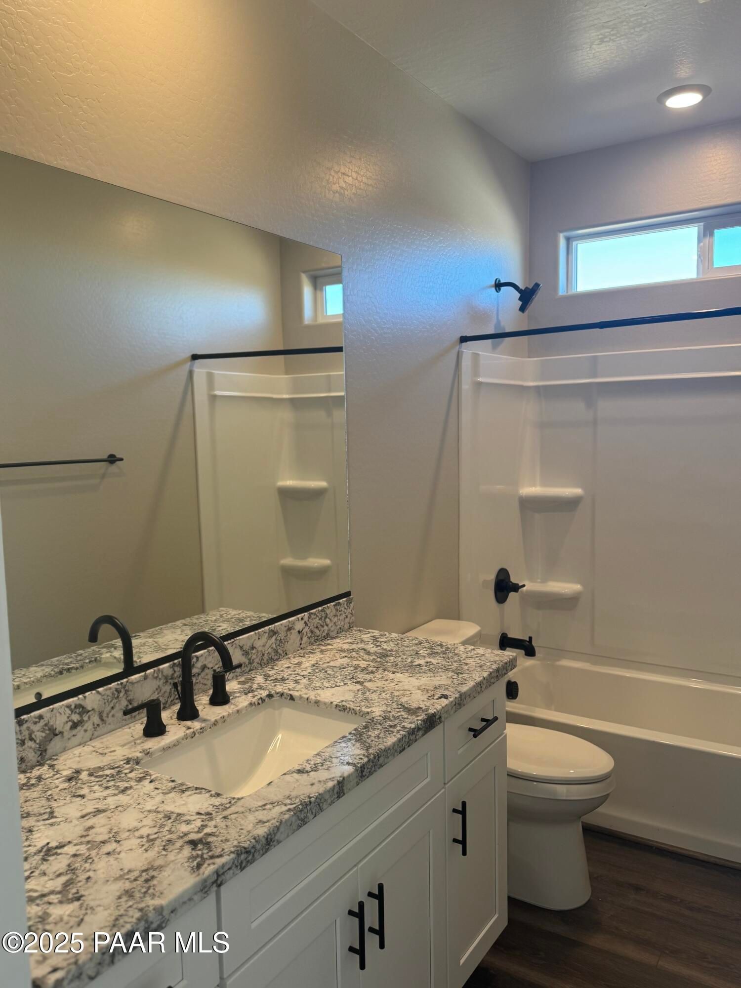Modern bathroom with white quartz vanity, black fixtures, bathtub shower combo in Davidson Homes The Monarch E, Prescott Arizona