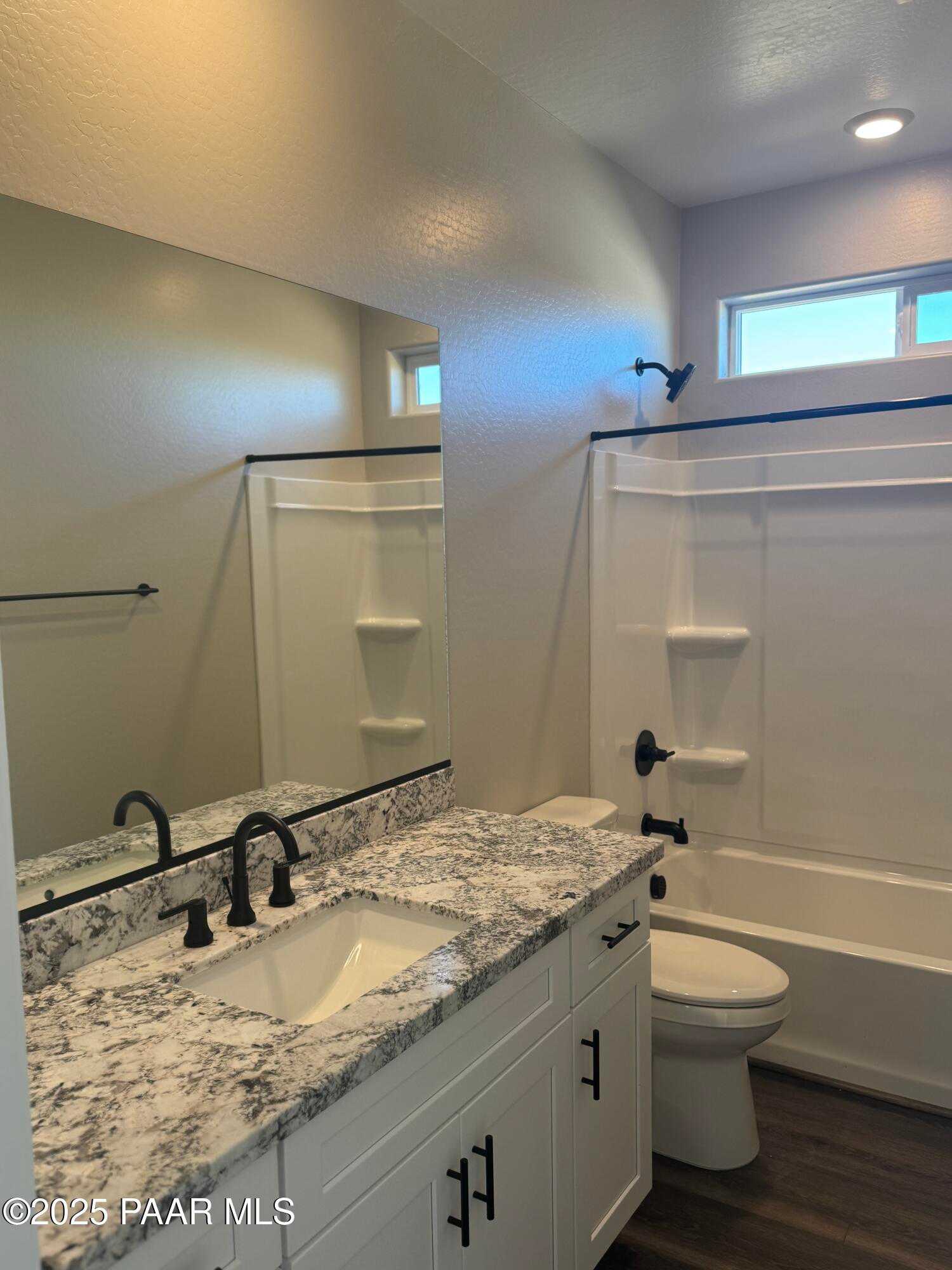 Modern bathroom with white quartz vanity, black fixtures, bathtub shower combo in Davidson Homes The Monarch E, Prescott Arizona