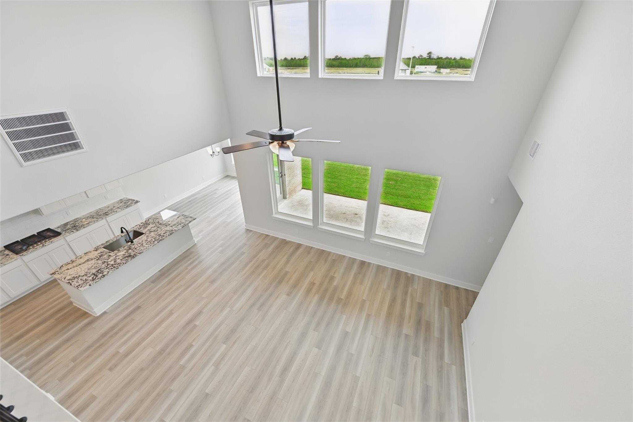 Spacious open-concept kitchen with granite island, white cabinets, and large windows overlooking lawn in Davidson Homes The Victoria C, Lago Mar