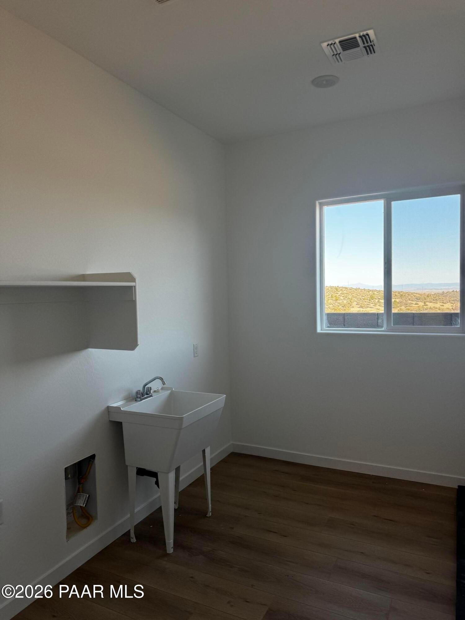 Bright laundry room with white utility sink, shelves and desert view window in Davidson Homes The Blaze C, Prescott, Arizona