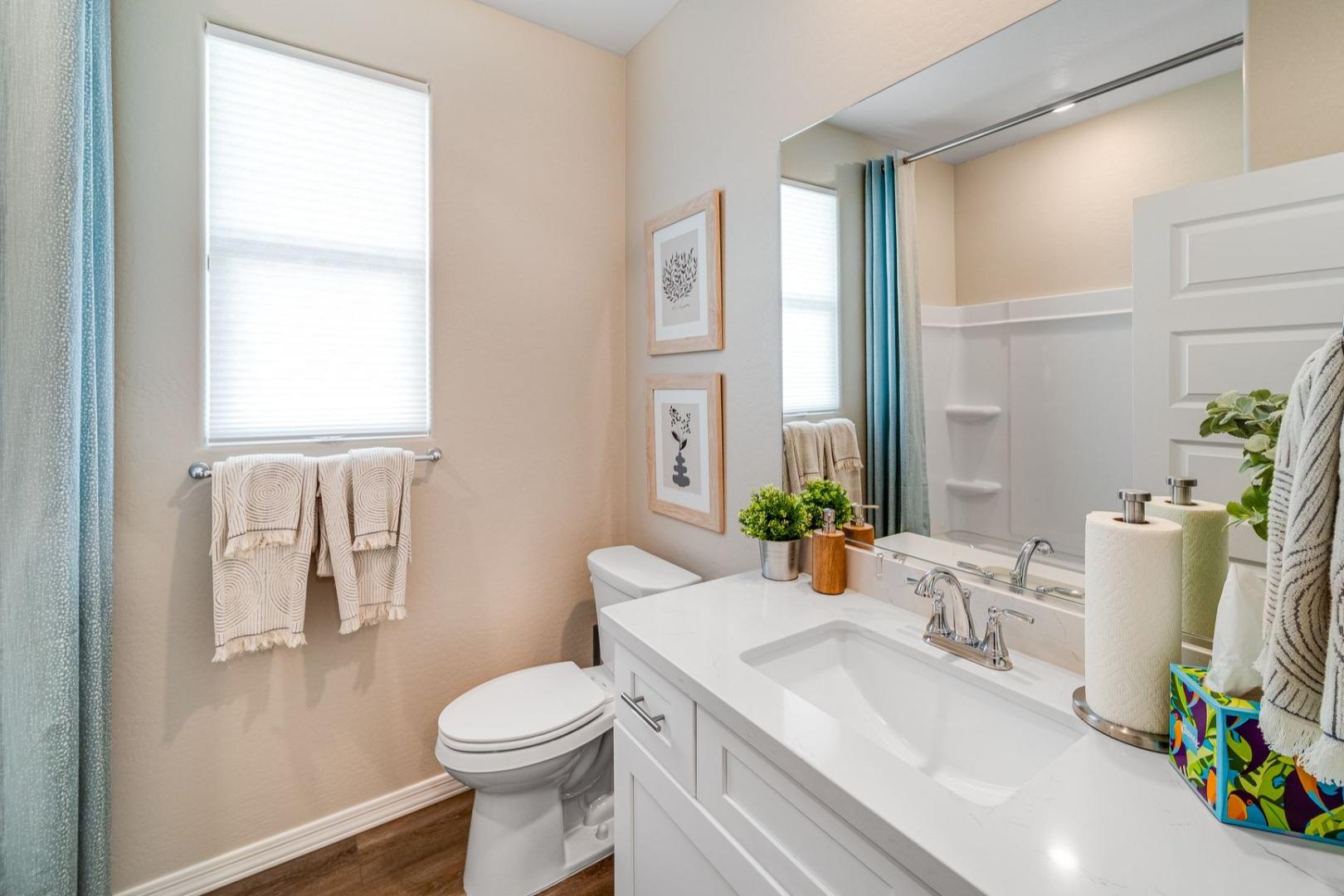 Modern master bathroom in The Newport with white vanity, walk-in shower, blue curtain, towels, and neutral beige walls