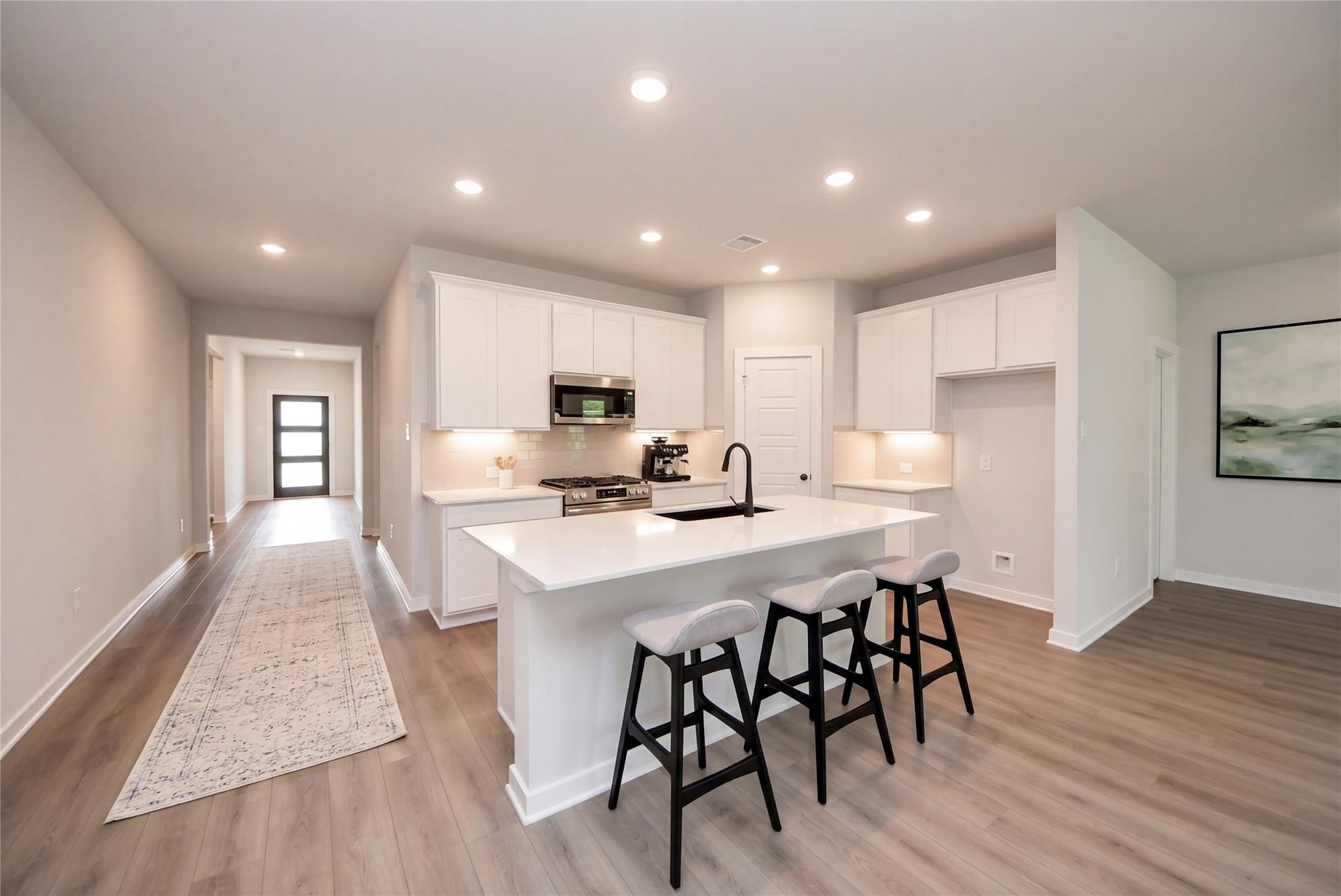 Bright open-concept kitchen with white cabinetry, large island, and black barstools in Davidson Homes Daphne F plan, Crosby, TX
