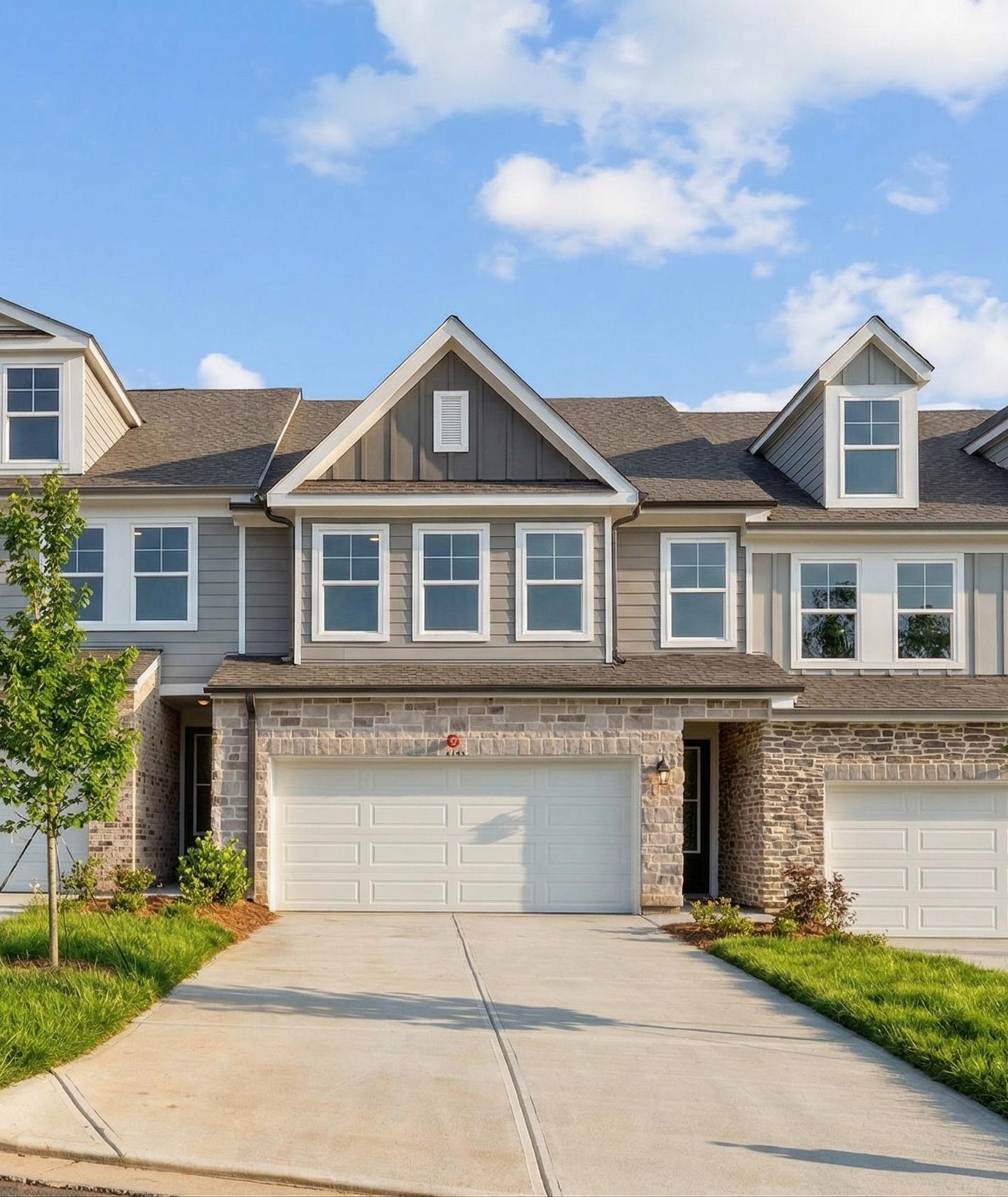 Modern townhouse exterior at Hemingway in Cumming, Georgia, featuring stone facade, gray siding, and attached garages.