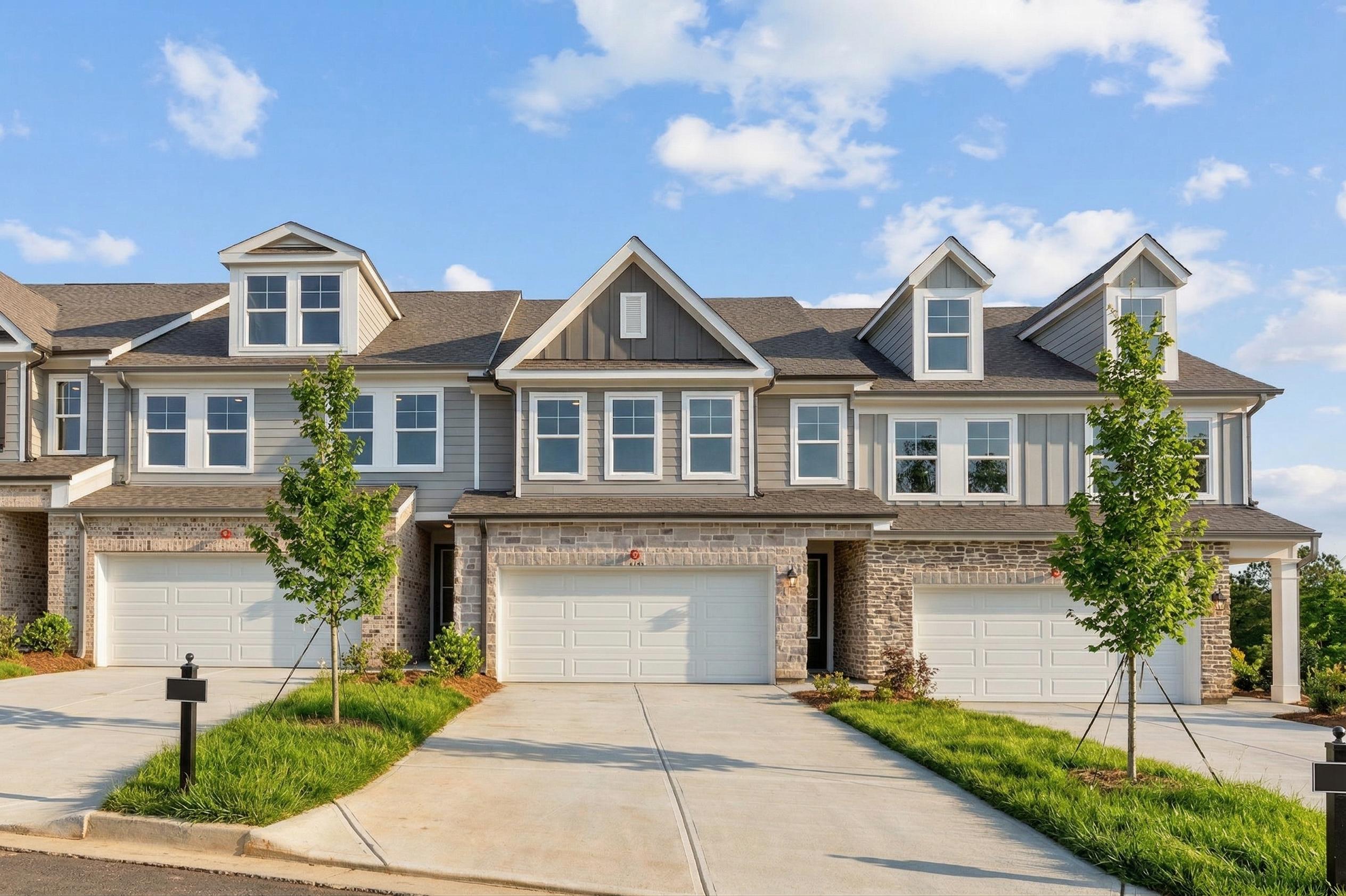 Modern townhouse exterior at Hemingway in Cumming, Georgia, featuring stone facade, gray siding, and attached garages.