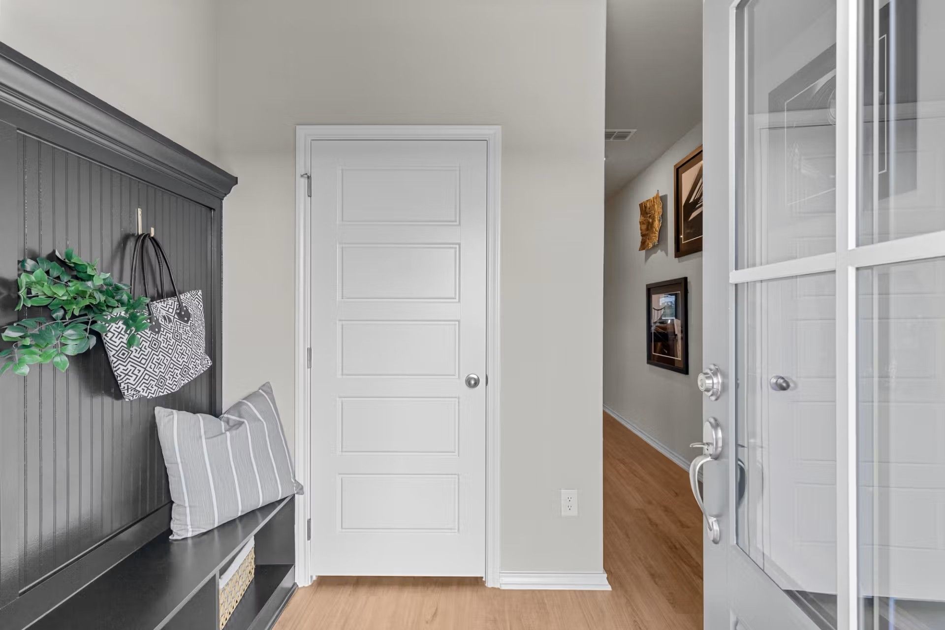 Entryway mudroom bench with coat hooks and hallway view in The Sabine H floor plan by Davidson Homes in Heartland, Texas.