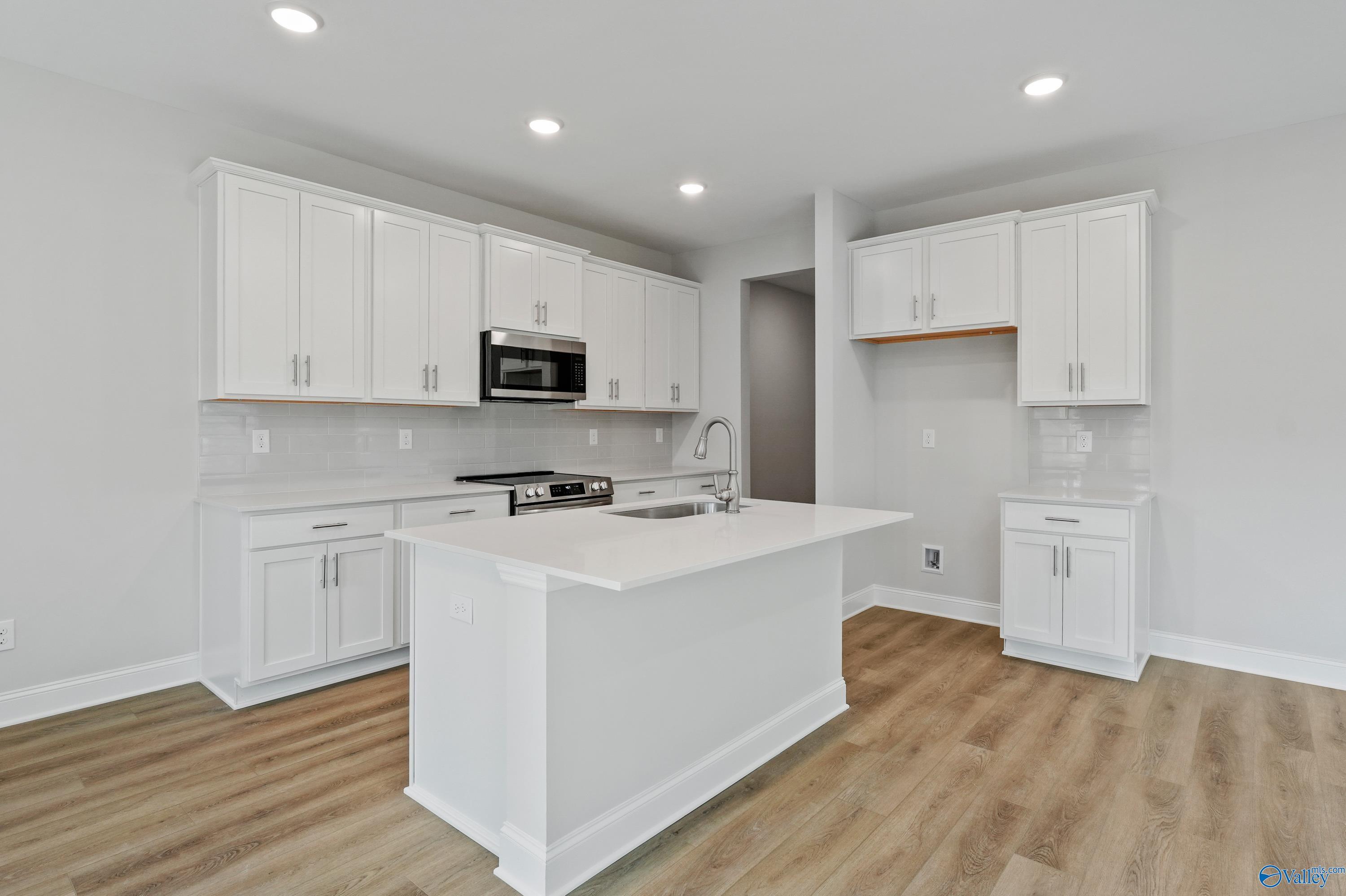Modern white kitchen island with stainless appliances and quartz counters in Davidson Homes The Camden, Huntsville AL