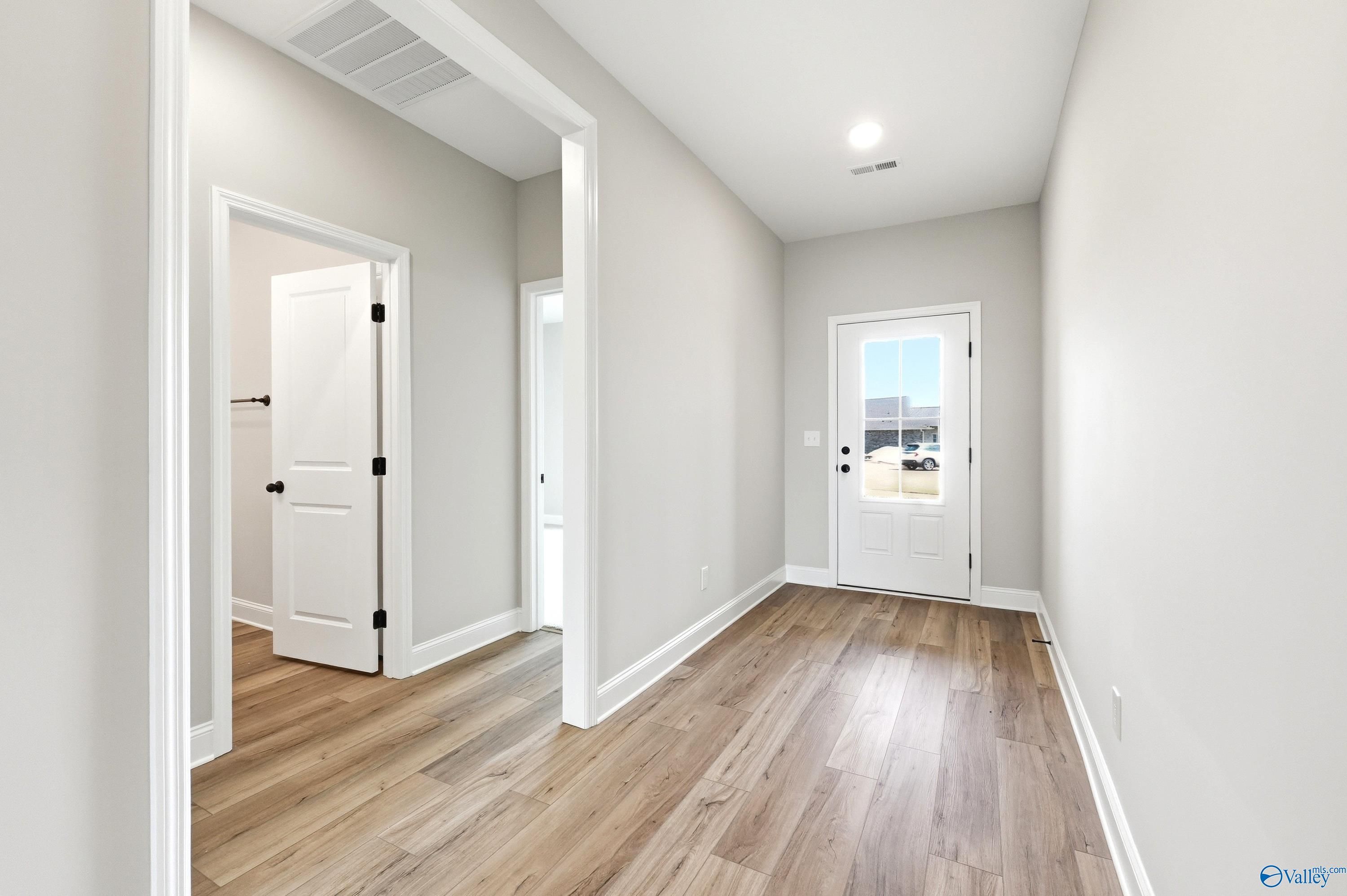 Bright entryway with wood-style flooring and white doors in The Daphne D floor plan by Davidson Homes in Harvest, AL.