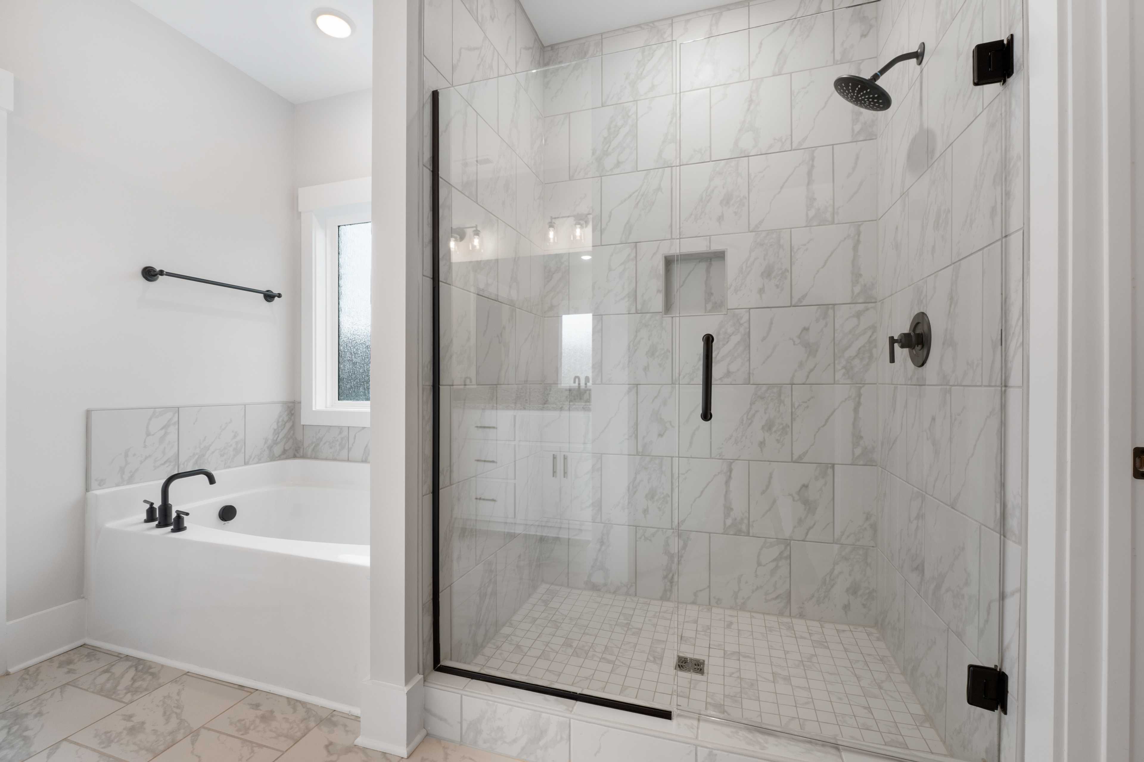 Luxury master bathroom at The Villas at Barnett's Crossing in Madison AL with marble tile shower, glass enclosure, and freestanding tub