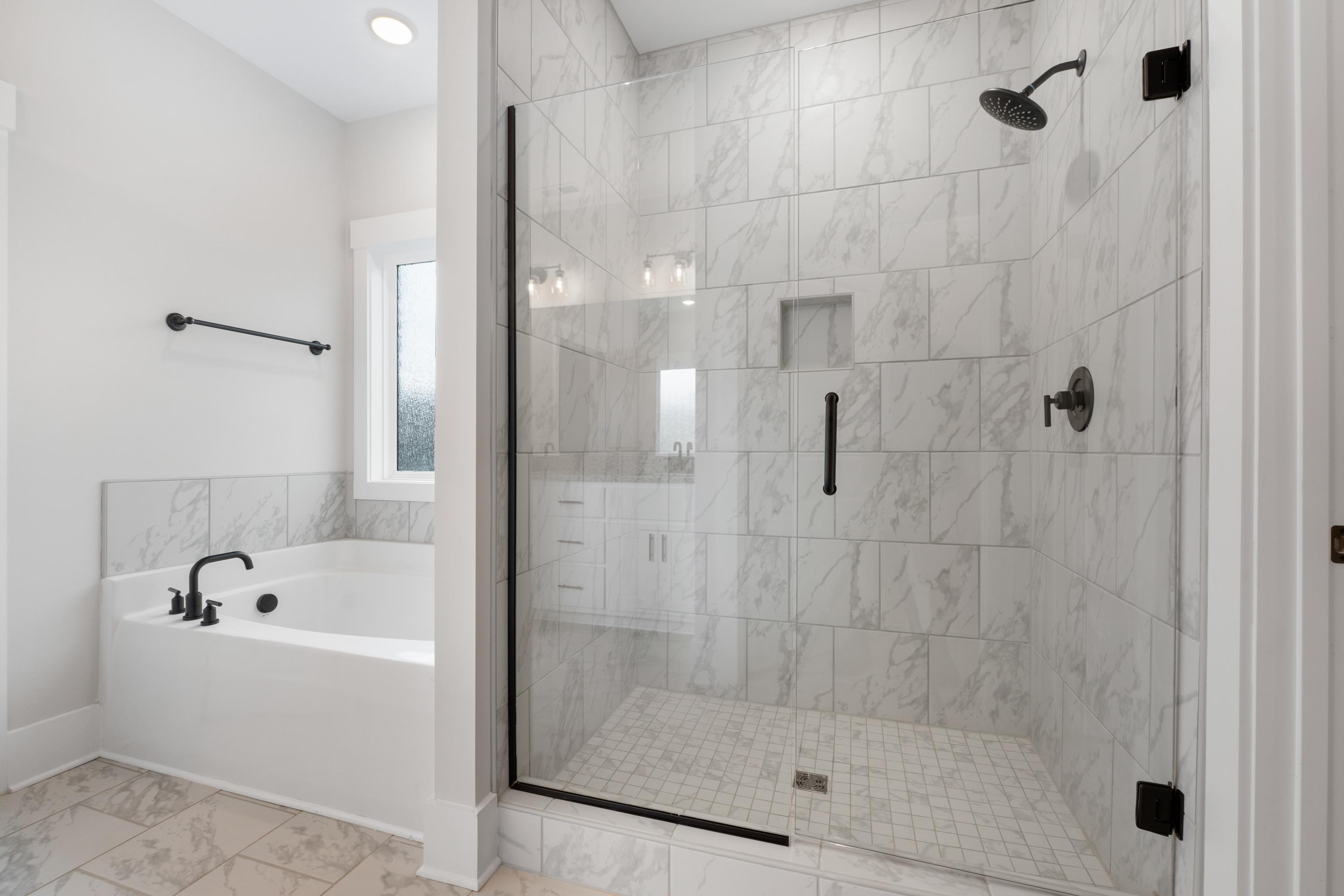 Luxury master bathroom at The Villas at Barnett's Crossing in Madison AL with marble tile shower, glass enclosure, and freestanding tub