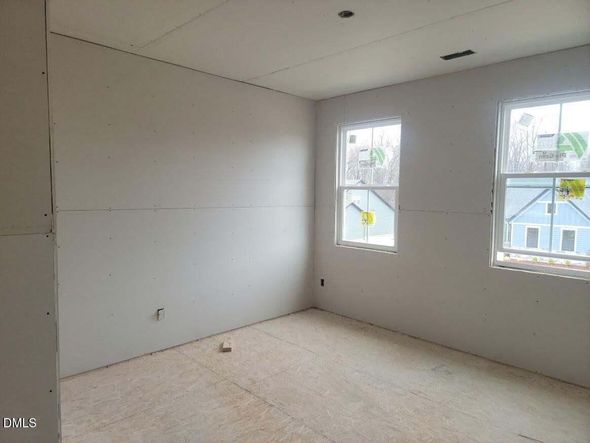 Unfinished bedroom with exposed subfloor, drywall walls, and two windows in Davidson Homes Ashport G, Angier, NC