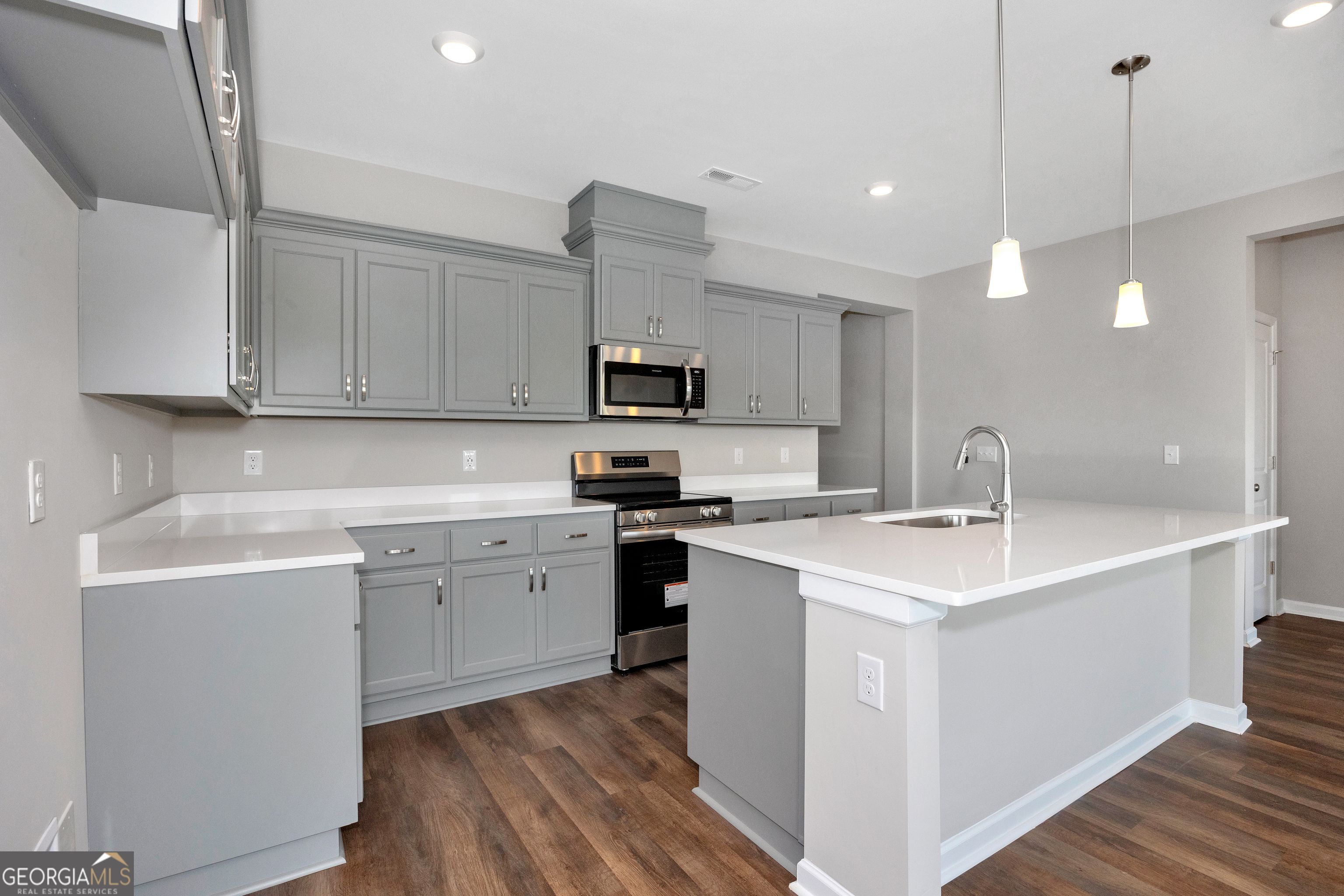 Modern gray kitchen with white quartz island, stainless appliances in The Luna 4-bedroom home by Evermore Homes in Perry, Georgia
