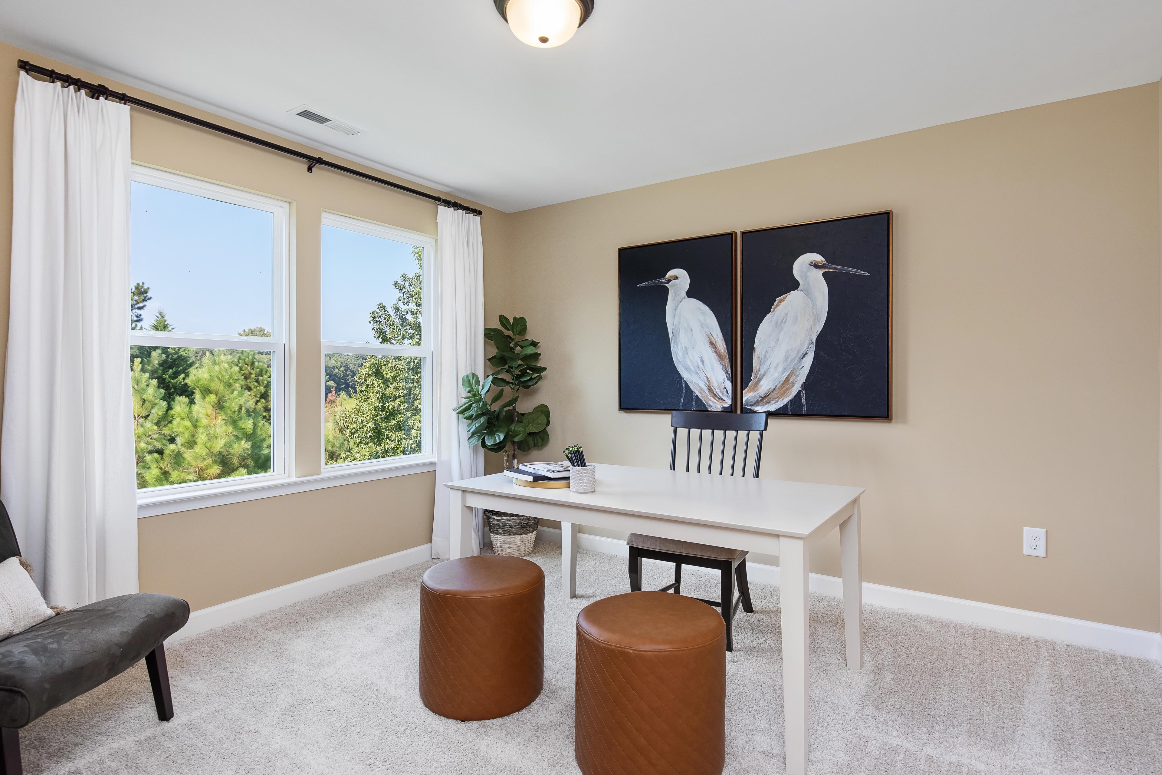 Cozy home office at Woodland Crossing in Zebulon NC with large windows, egret wall art, white desk, and leather stools