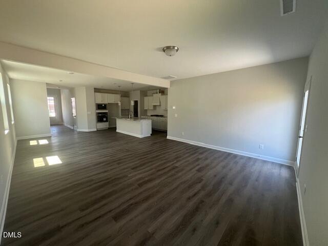 Open-concept kitchen-living space with white island, cabinets, stainless appliances, luxury vinyl plank floors in Davidson Homes Adalynn A, Lillington, NC