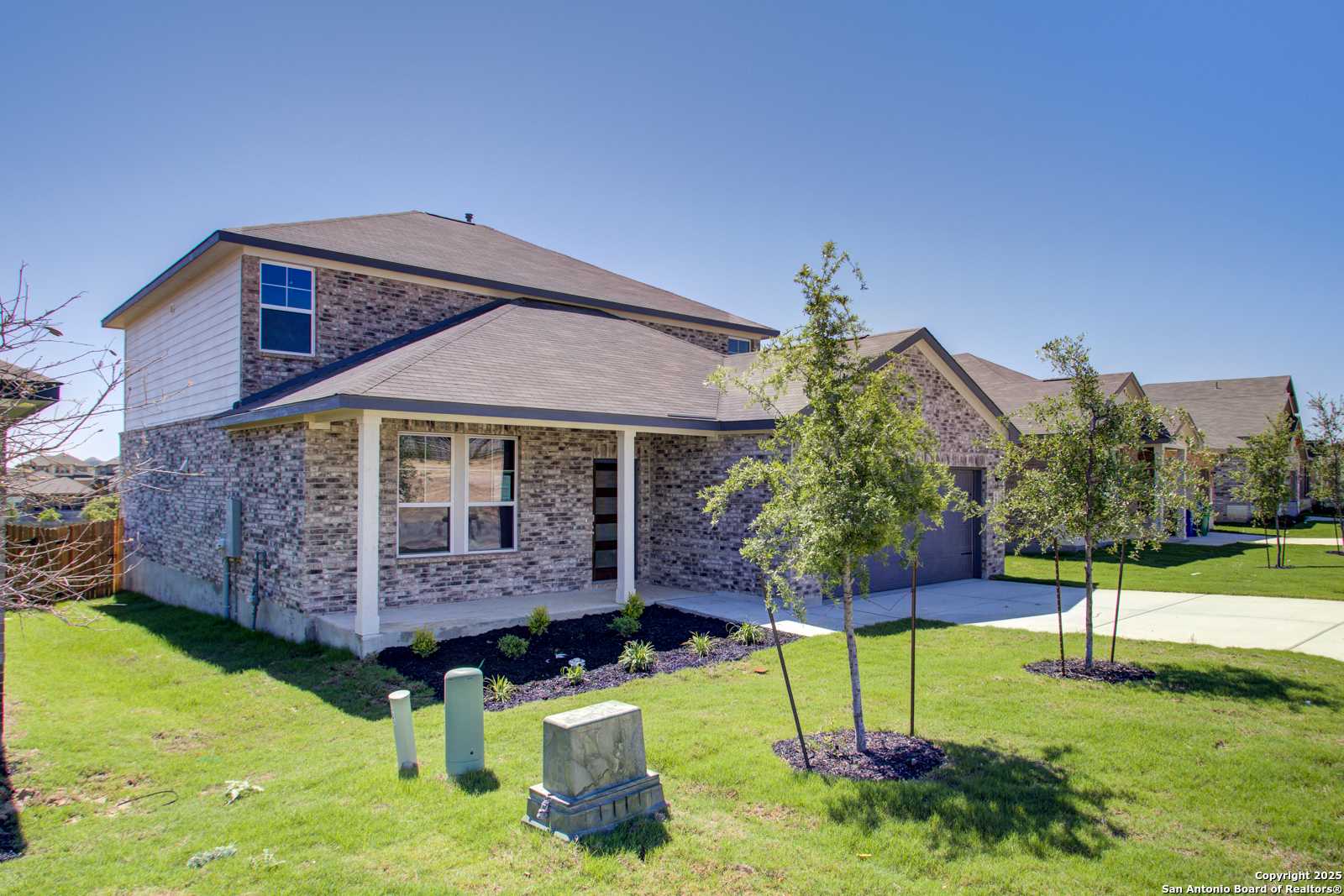 Two-story brick home with 2-car garage, front porch, and landscaped yard in Comanche Ridge, San Antonio, Texas - Davidson Homes The Douglas G