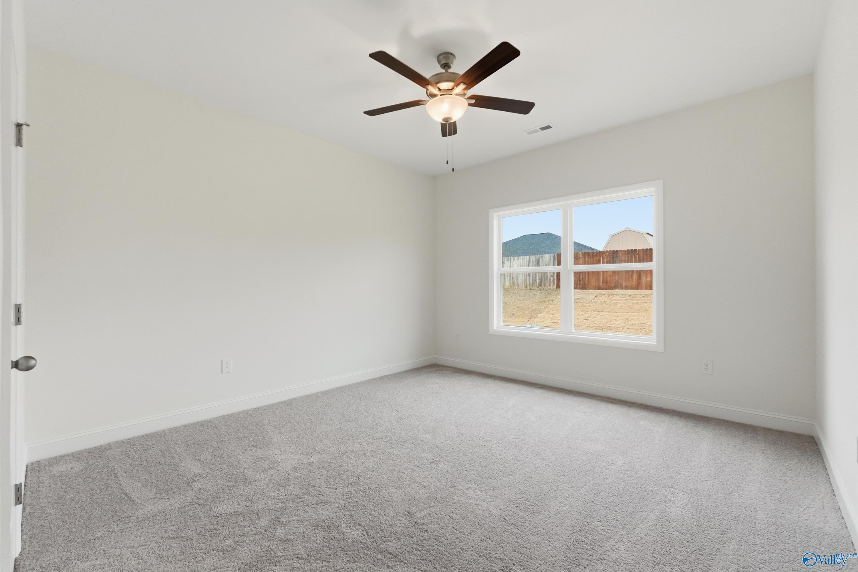 Bright secondary bedroom with ceiling fan, gray carpet, and window overlooking yard in Davidson Homes The Asheville C, Meridianville