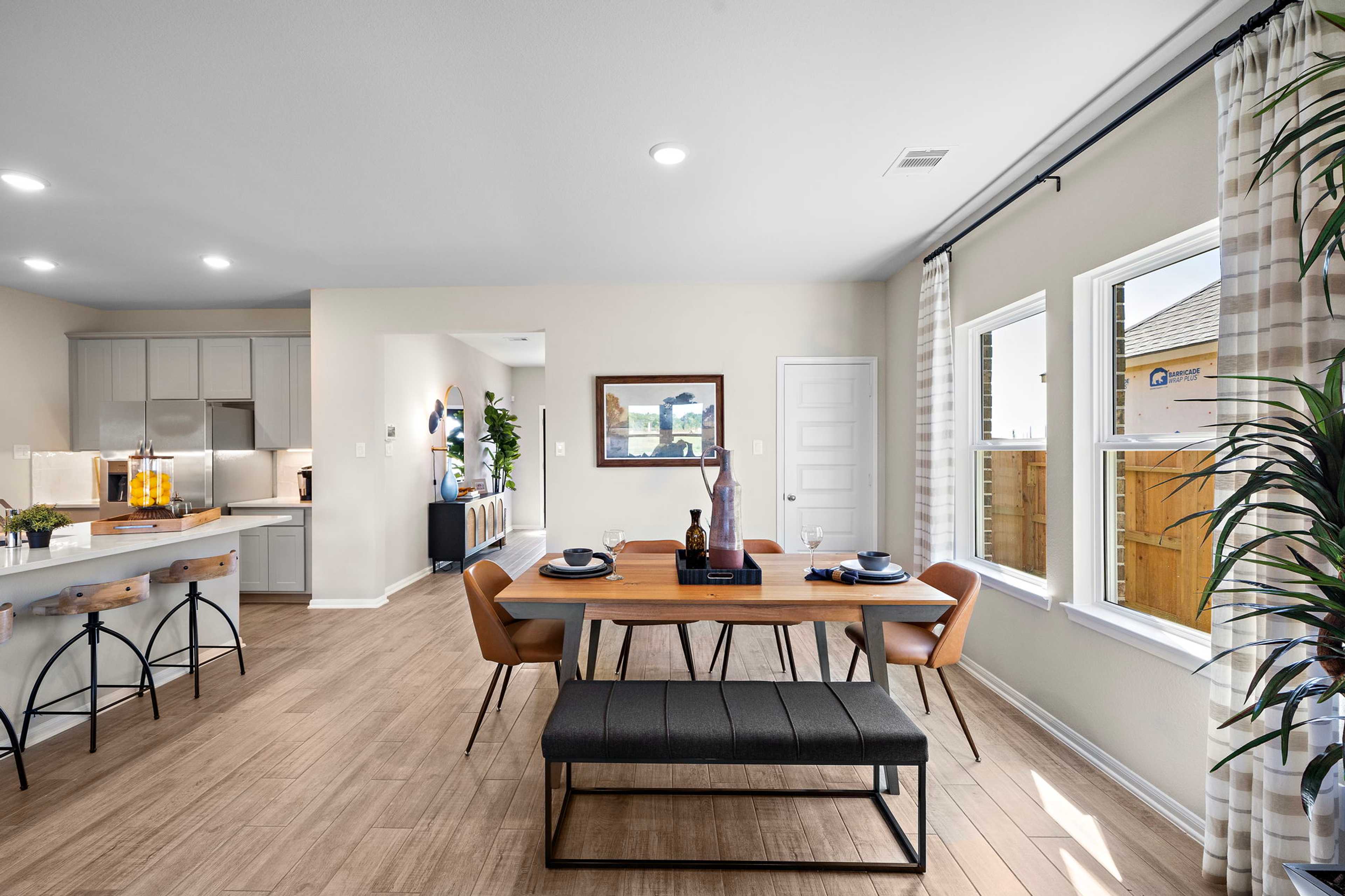 Spacious open-concept kitchen dining in Emberly Beasley TX with hardwood floors gray cabinets large windows and modern seating