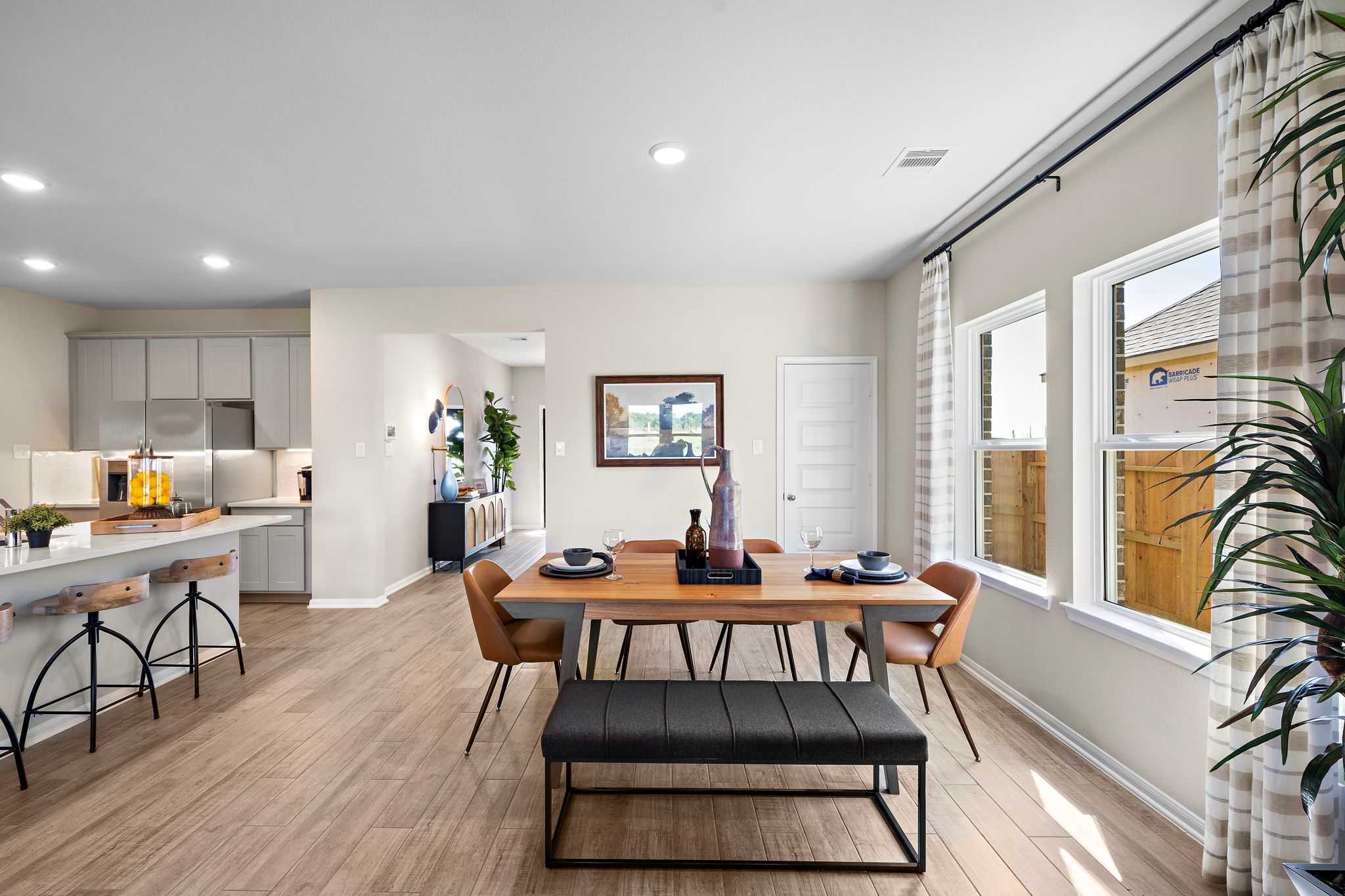 Spacious open-concept kitchen dining in Emberly Beasley TX with hardwood floors gray cabinets large windows and modern seating