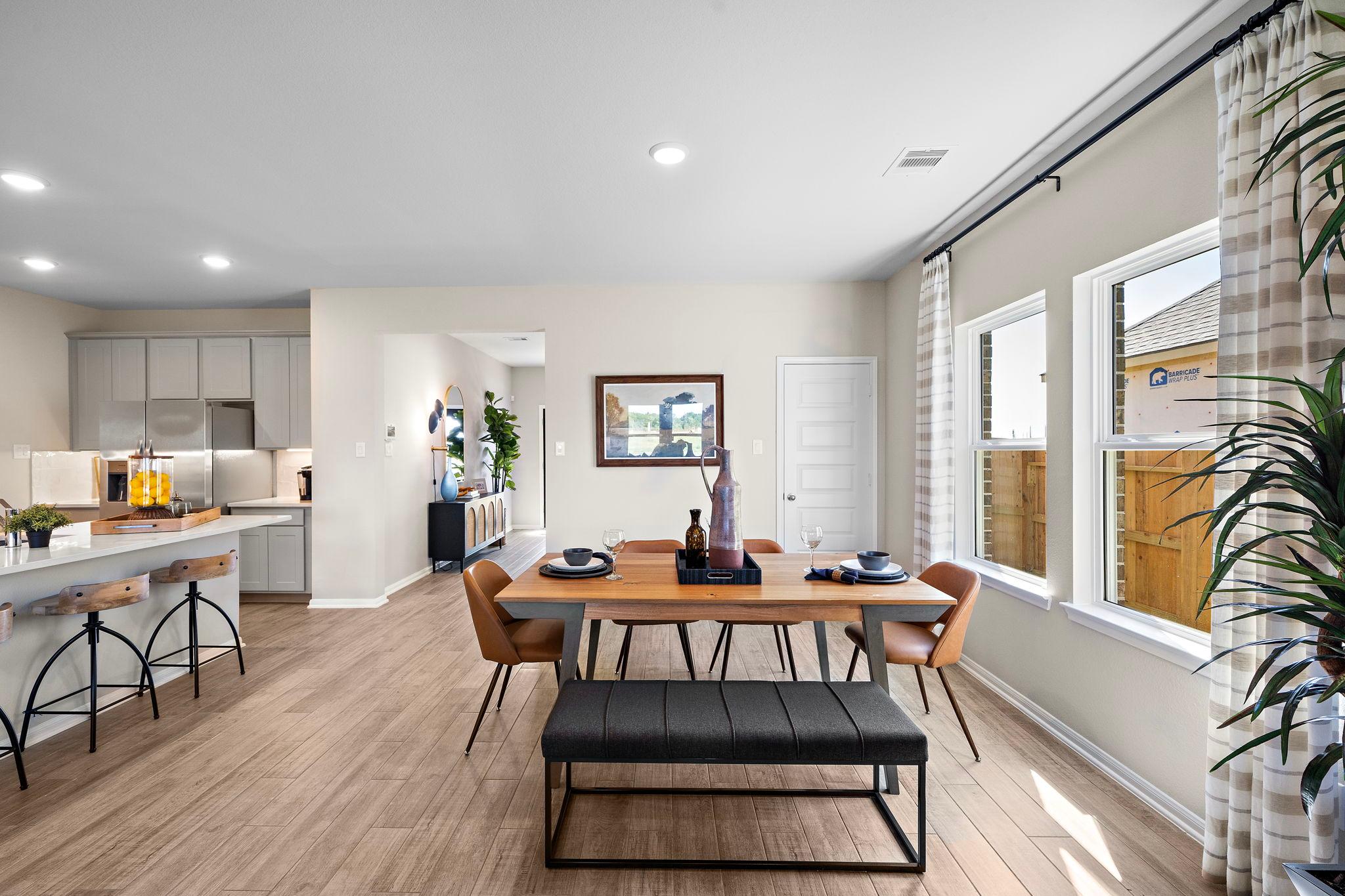 Spacious open-concept kitchen dining in Emberly Beasley TX with hardwood floors gray cabinets large windows and modern seating