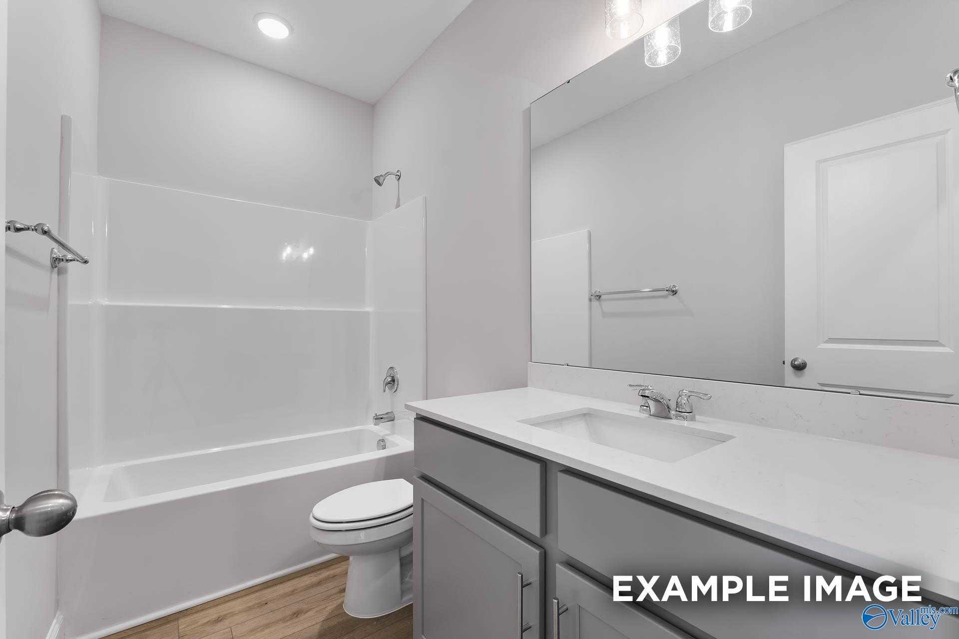 Modern guest bathroom featuring tub-shower combo, white vanity, and large mirror in Davidson Homes The Daphne C, New Market, Alabama