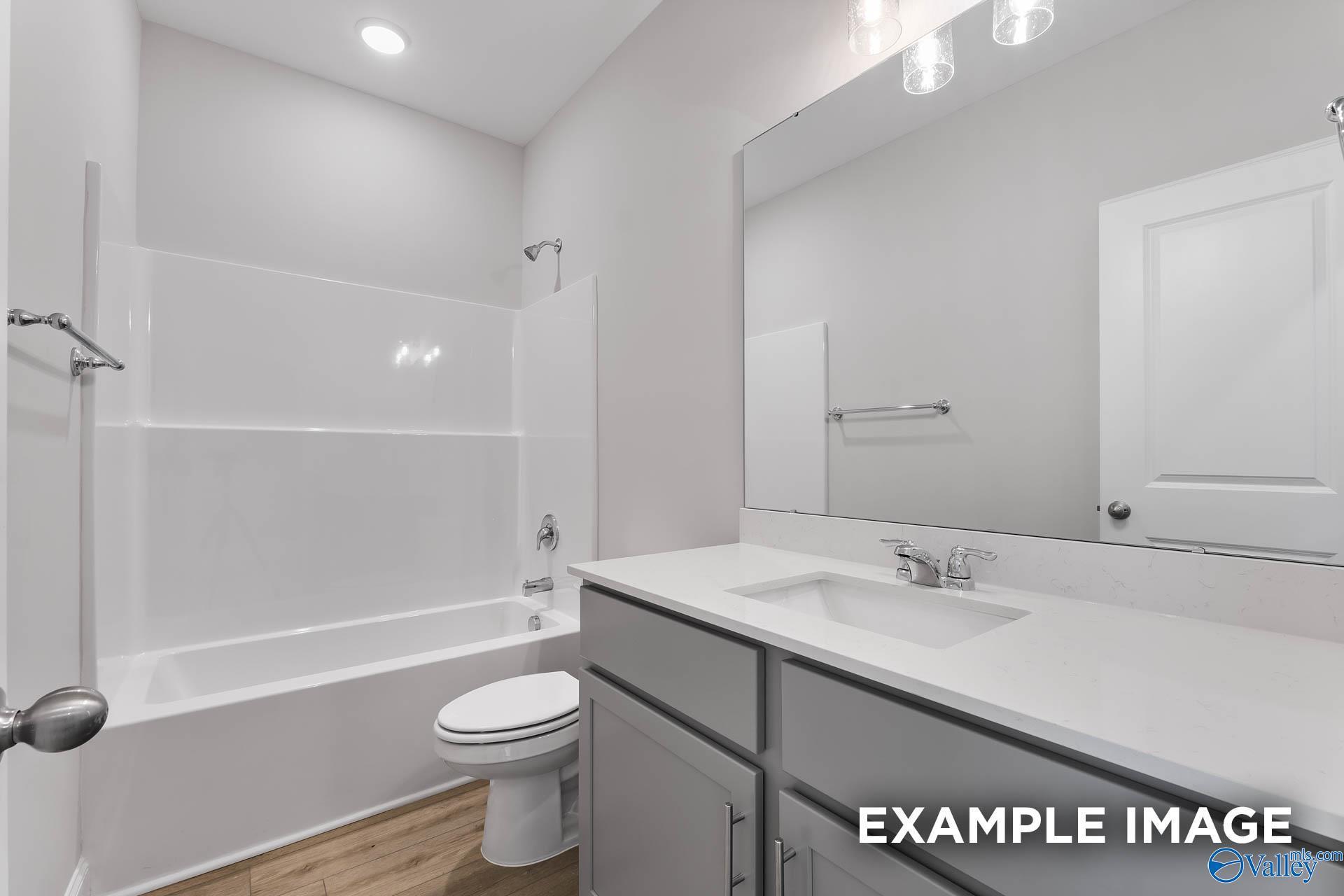 Bright secondary bathroom with white tub-shower combo, single vanity, and modern fixtures in Davidson Homes The Daphne C, Toney, Alabama