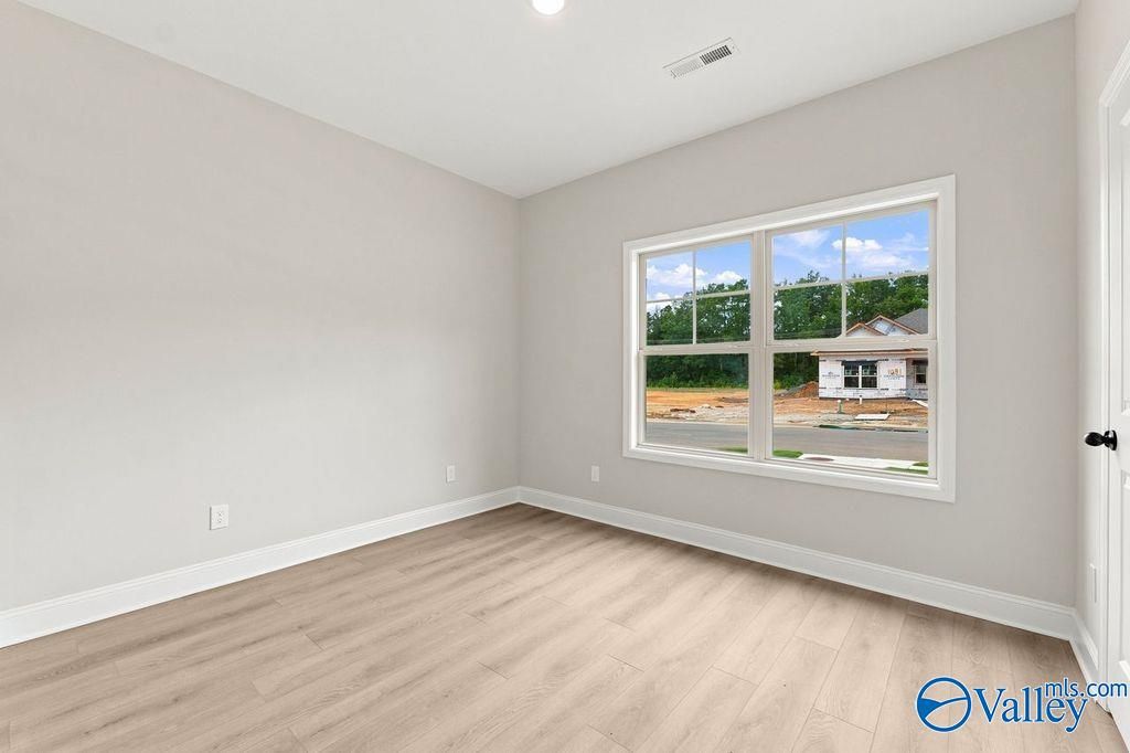 Bright bedroom with neutral walls and wood-look flooring in The Camilla B floor plan at The Retreat at Cain Park, Hartselle.