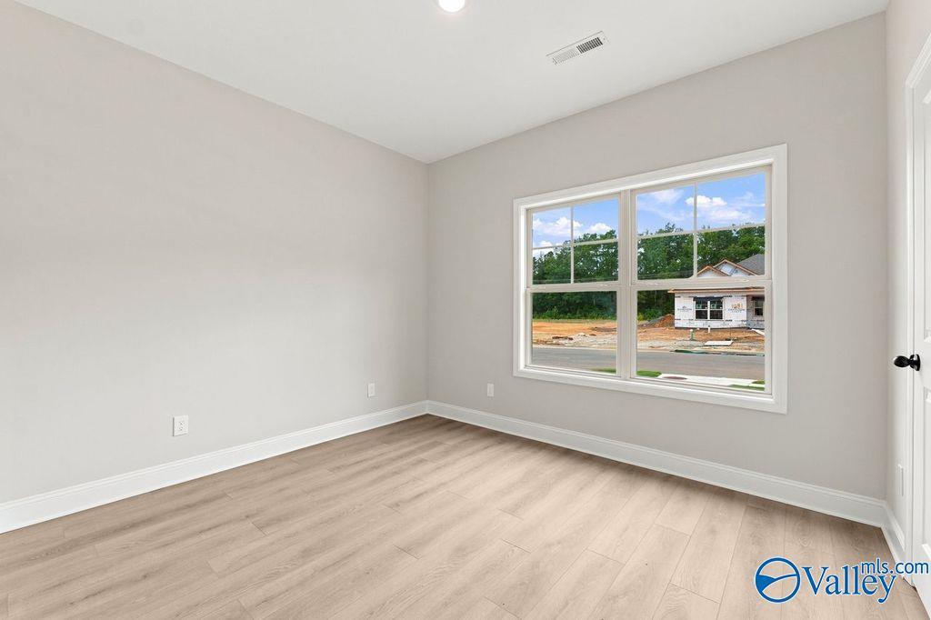 Bright bedroom with neutral walls and wood-look flooring in The Camilla B floor plan at The Retreat at Cain Park, Hartselle.