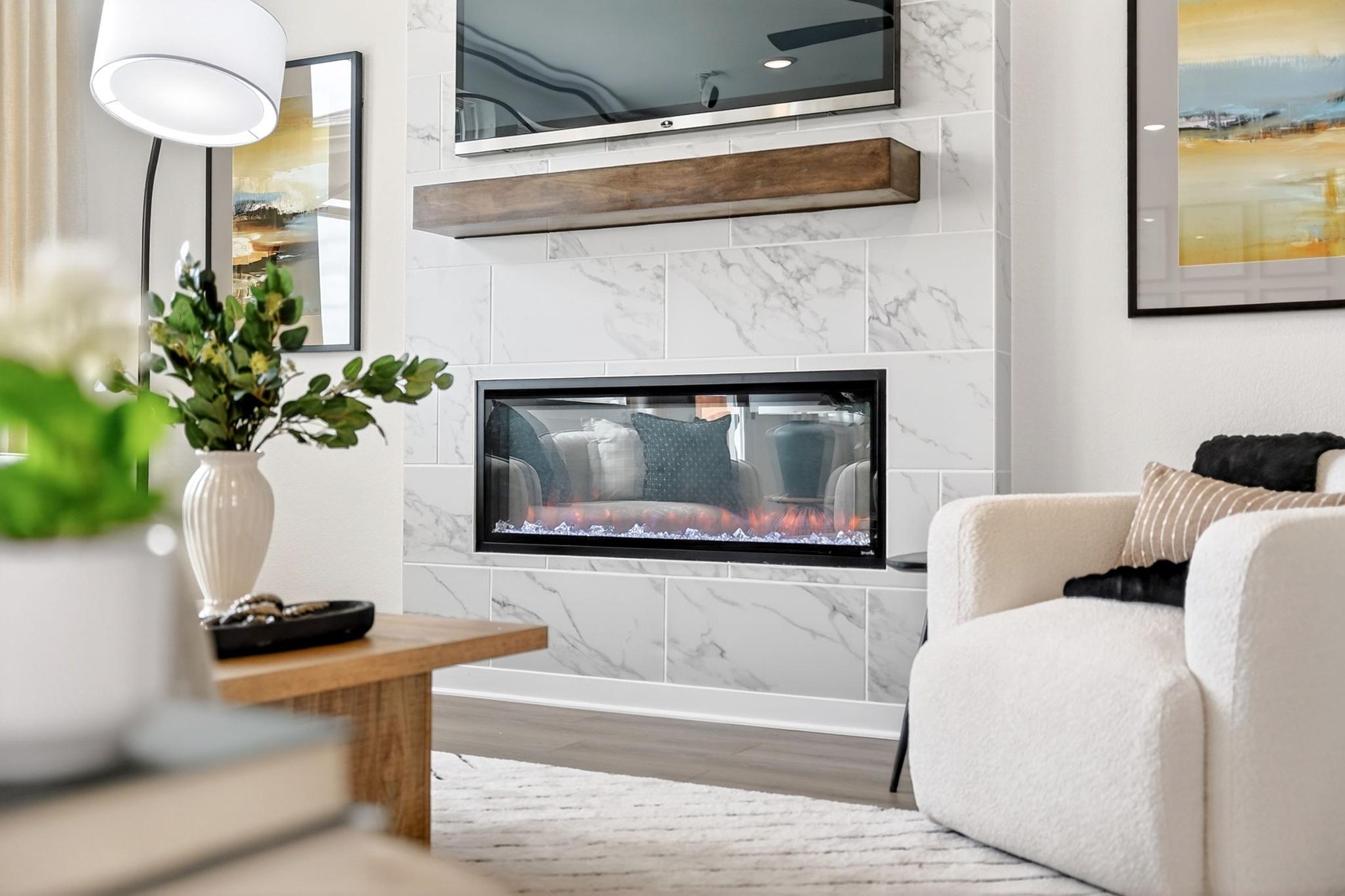 Modern fireplace with marble tile surround and wood mantel at Parks at Foster Crossing in Anna, TX by Davidson Homes