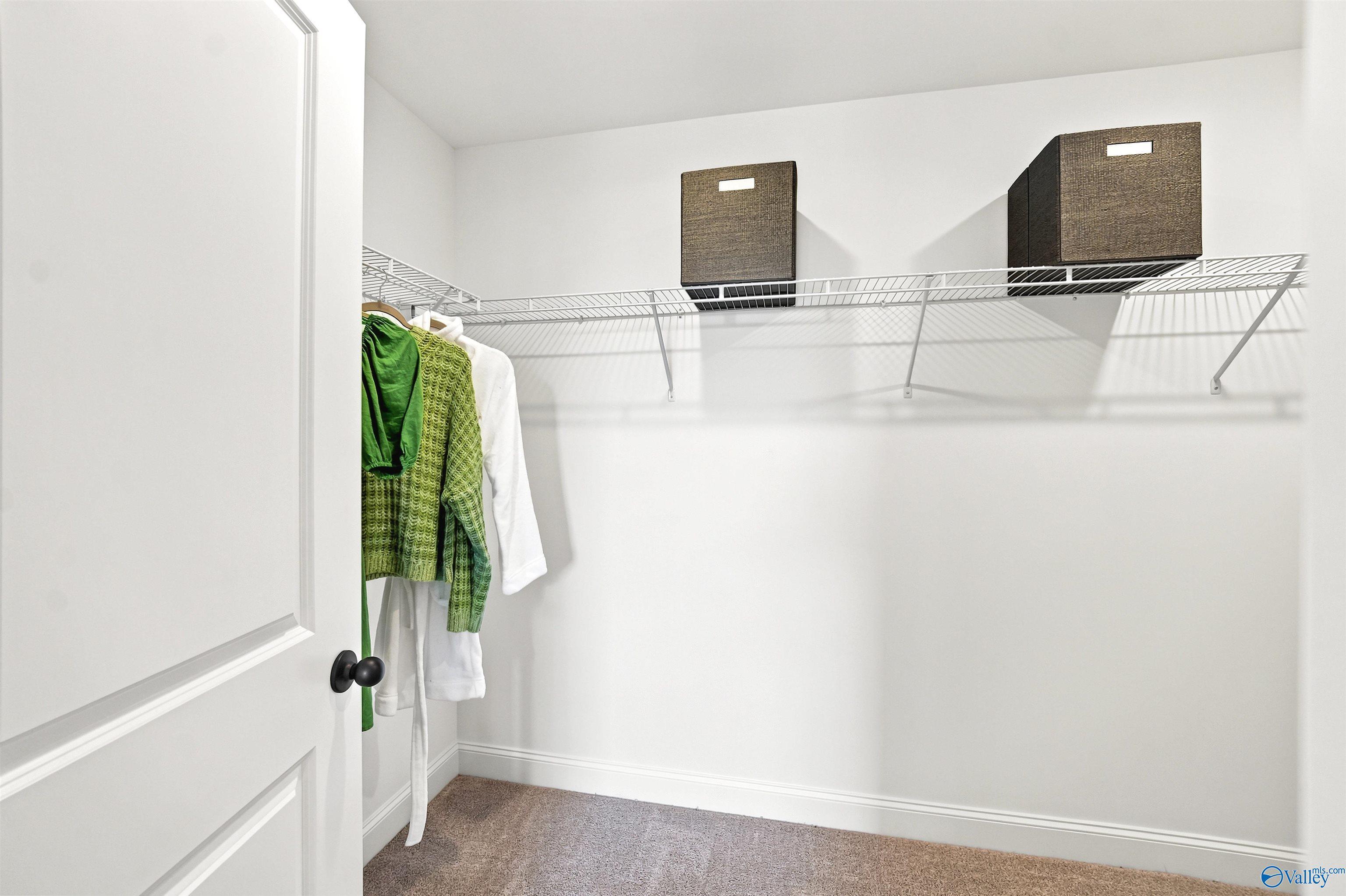 Walk-in closet with wire shelving and storage bins in The Burton B floor plan at Heritage Lakes, New Market, Alabama.