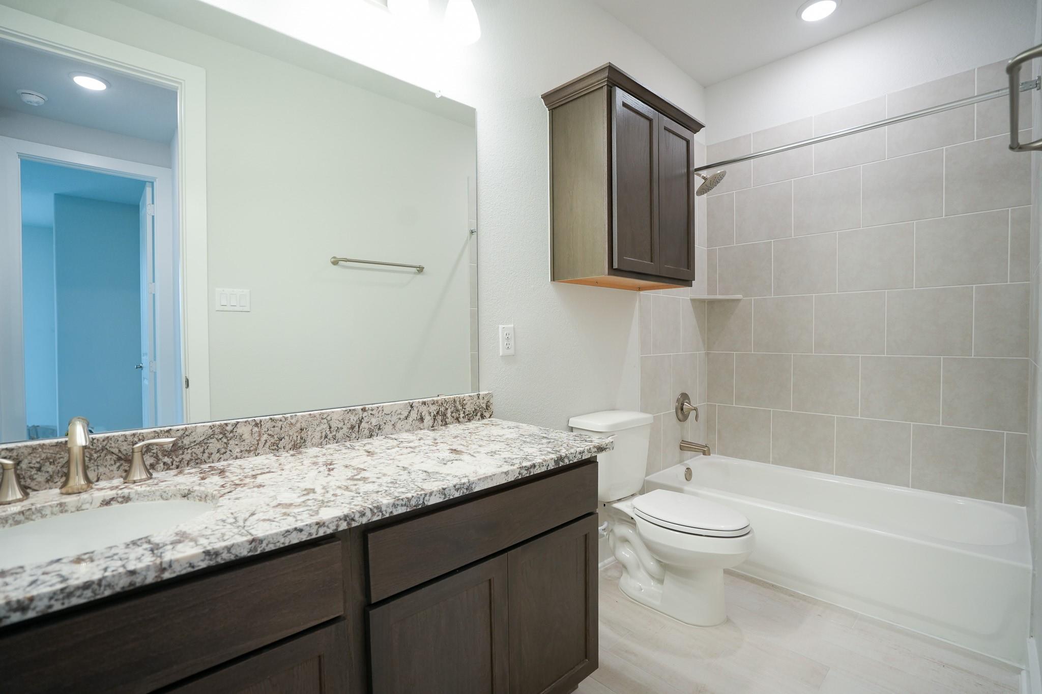 Modern bathroom featuring double vanity with quartz countertop, subway tile shower-tub combo in Davidson Homes The Edward C, Lago Mar, Texas City