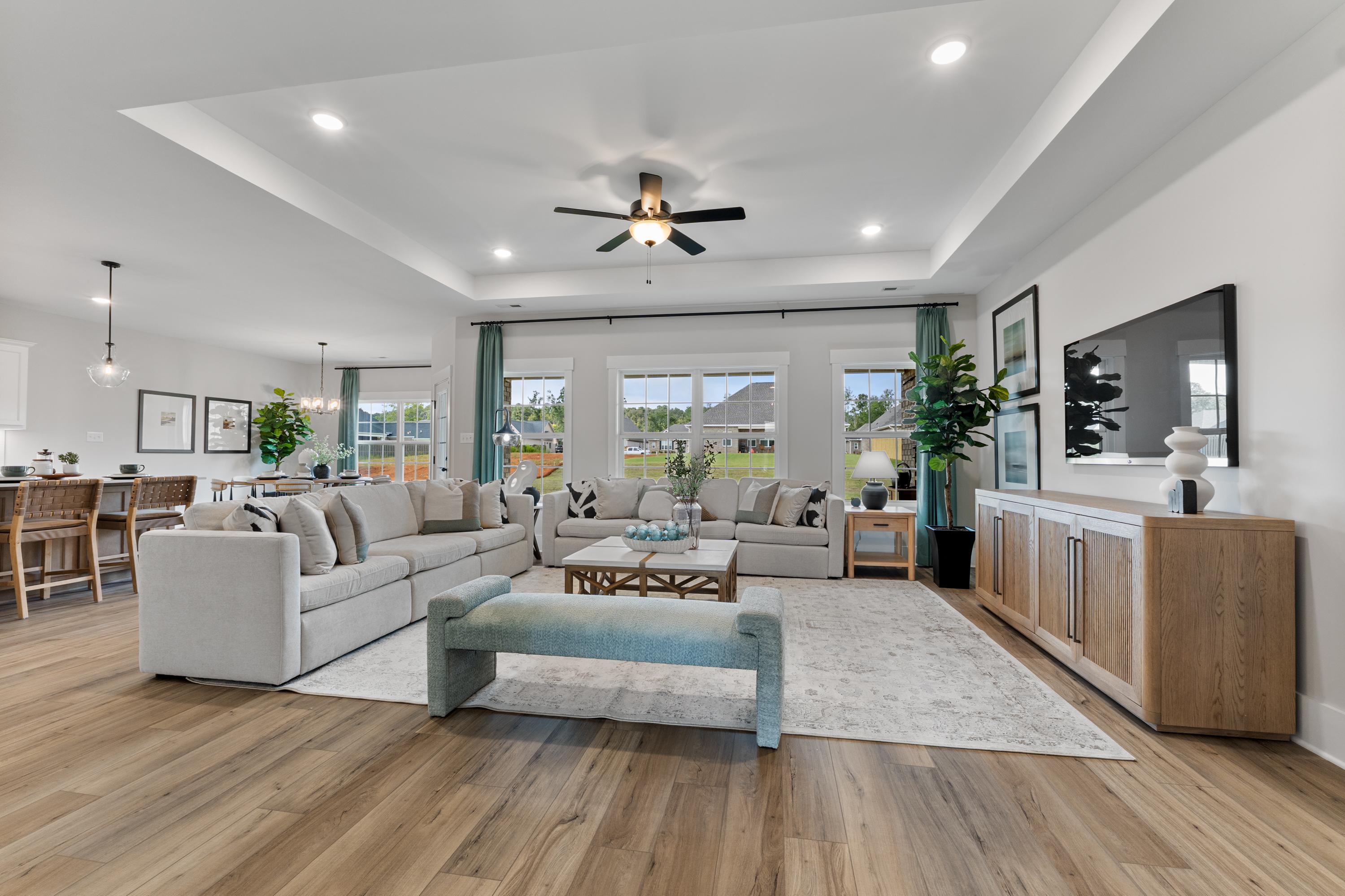 Spacious open-concept living room at River Road Estates in Decatur Alabama with beige sectional sofa, hardwood floors, and large windows