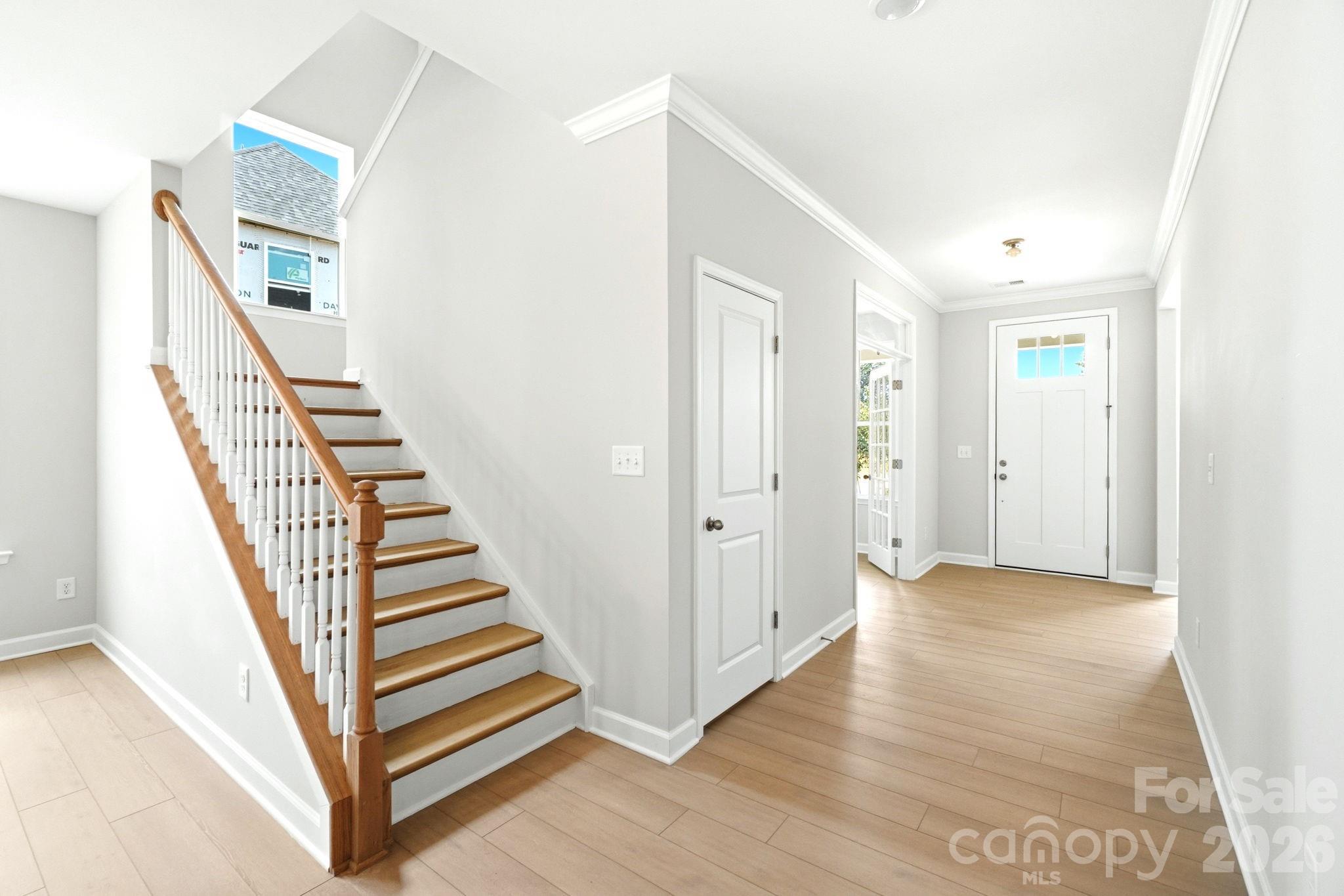 Bright entryway with hardwood floors and wooden staircase in The Magnolia B floor plan by Davidson Homes in Mooresville, NC.