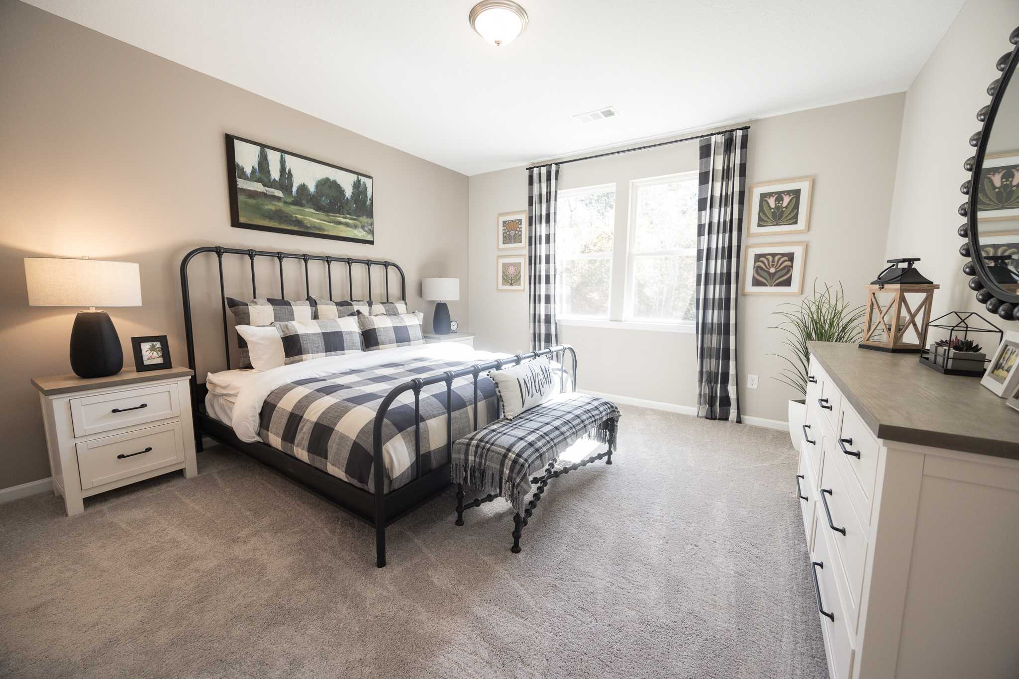Spacious master bedroom at Silver Oak in Cusseta Alabama with black metal bed frame, checkered bedding, and neutral walls