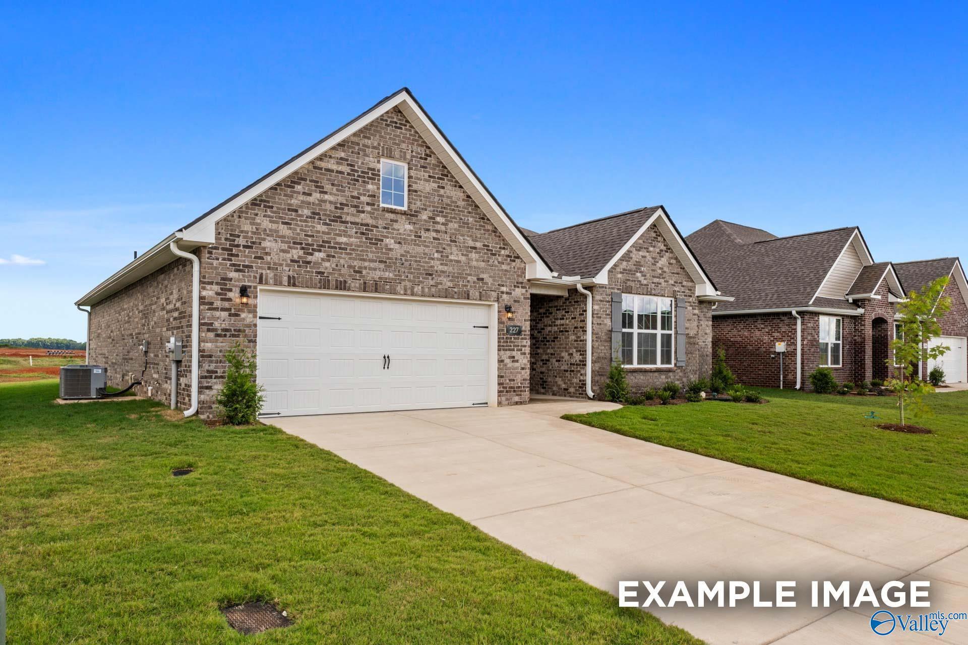 Modern brick 1-story home with 2-car garage, driveway, and lush lawn under blue sky in Creekside, Harvest, Alabama - Davidson Homes Montgomery