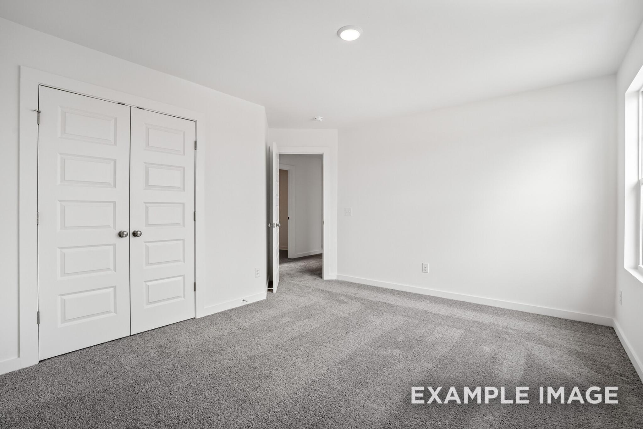 Spacious master bedroom in The Logan C with gray carpet, white double closet doors, and en-suite access