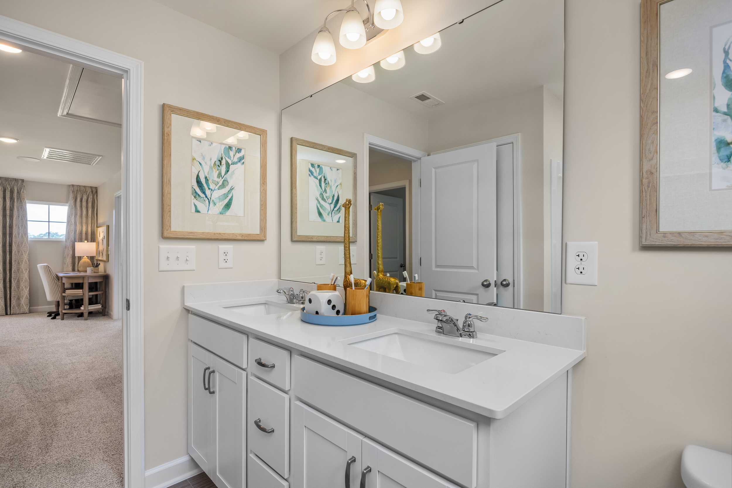 Spacious double vanity bathroom at Retreat at North Main in Lillington NC with white cabinets, leaf artwork and neutral tones