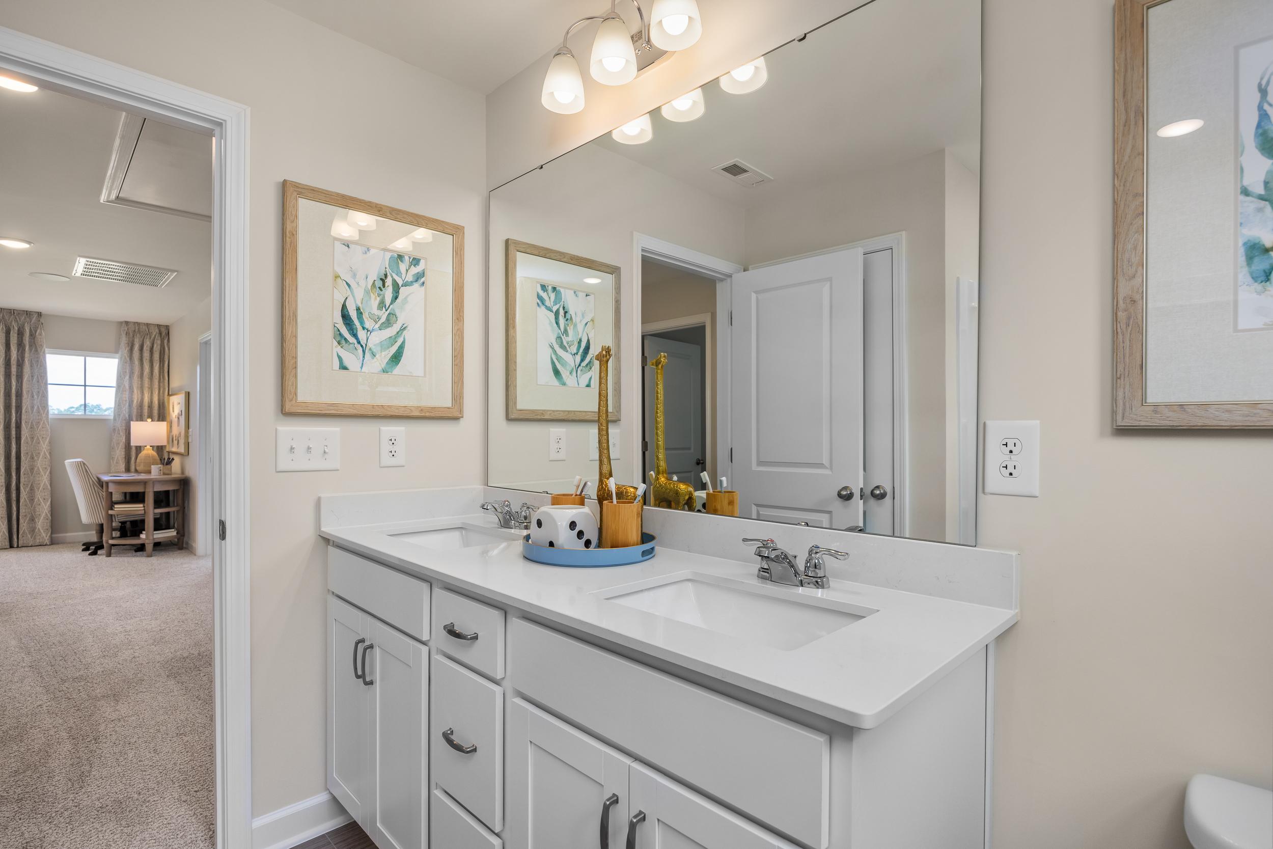 Spacious double vanity bathroom at Retreat at North Main in Lillington NC with white cabinets, leaf artwork and neutral tones