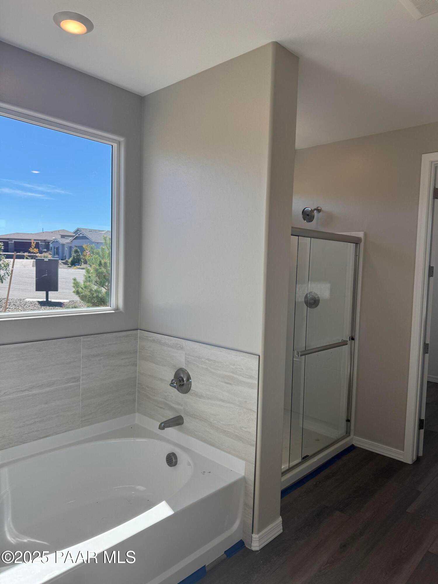 Elegant master bathroom featuring soaking tub, frameless glass shower, and mountain view window in The Monarch E, Prescott, AZ
