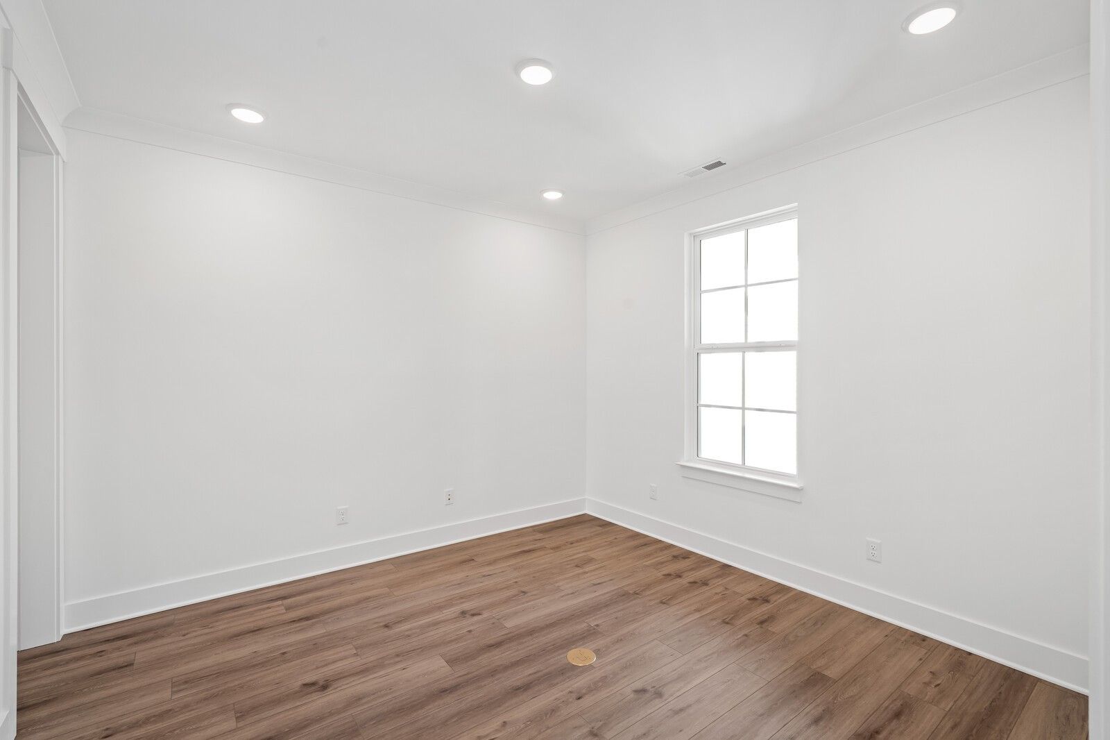 Bright empty bedroom with white walls, hardwood floors, large window, and recessed lighting in Davidson Homes The Hawkins, Murfreesboro, TN