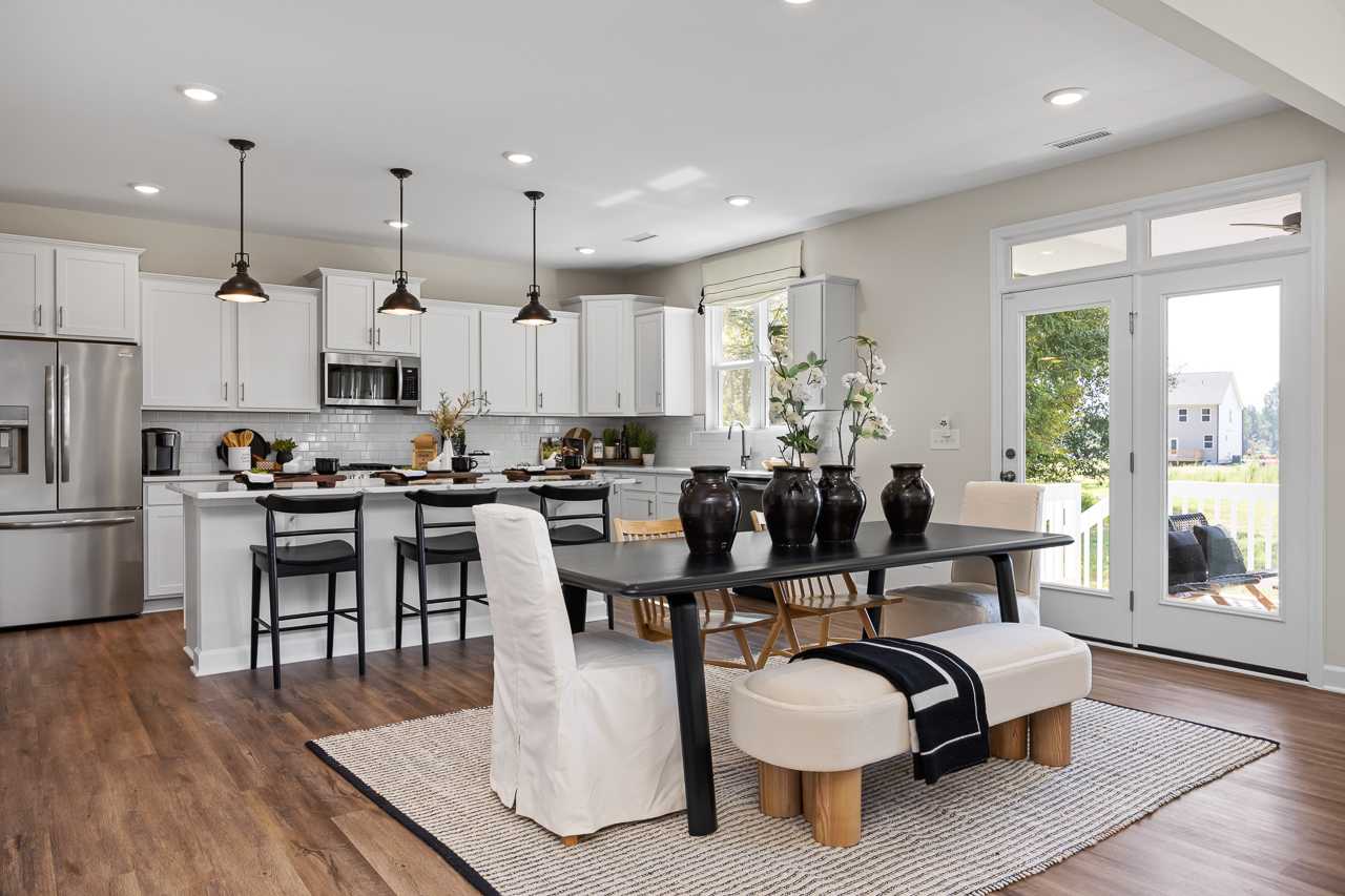Spacious open-concept kitchen and dining at Wellers Knoll in Lillington NC with white cabinets, stainless appliances, hardwood floors, and large windows