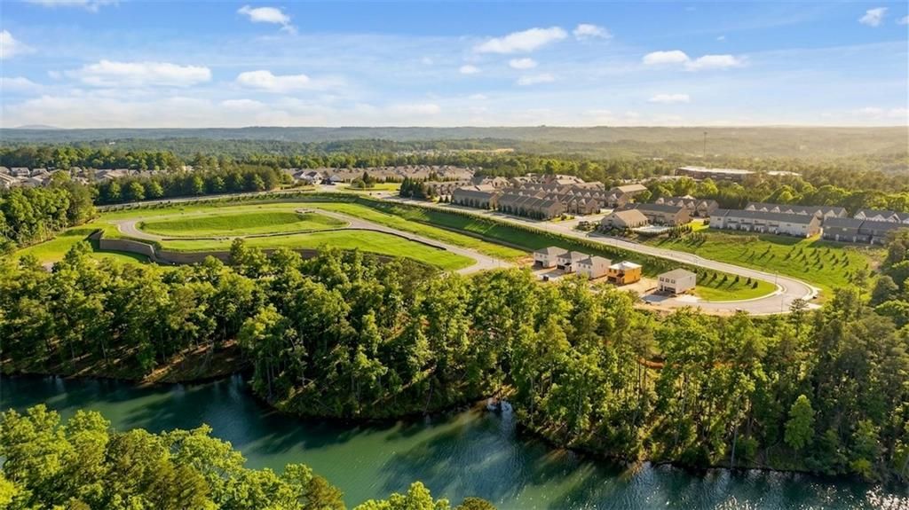 Aerial view of The Bluffs community in Canton, Georgia, with Davidson Homes townhomes, lush trees, green spaces, and scenic riverfront