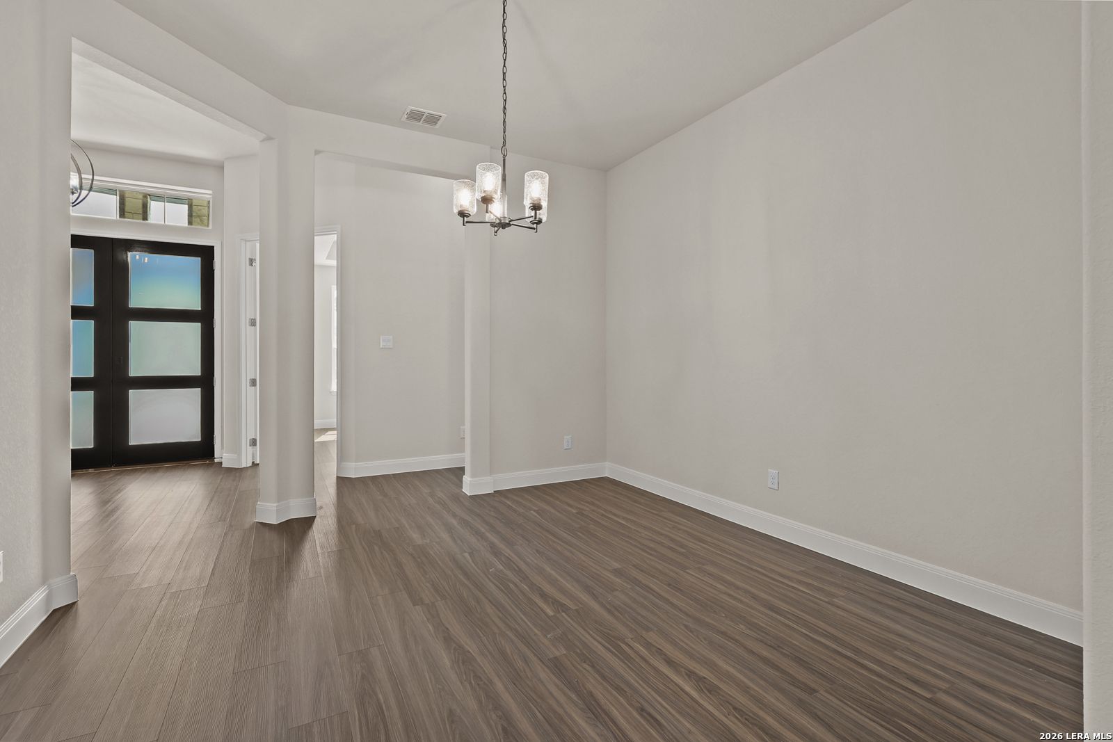 Elegant dining room with modern chandelier and wood-look flooring in The Summerlin B floor plan, Potranco Oaks, Castroville.