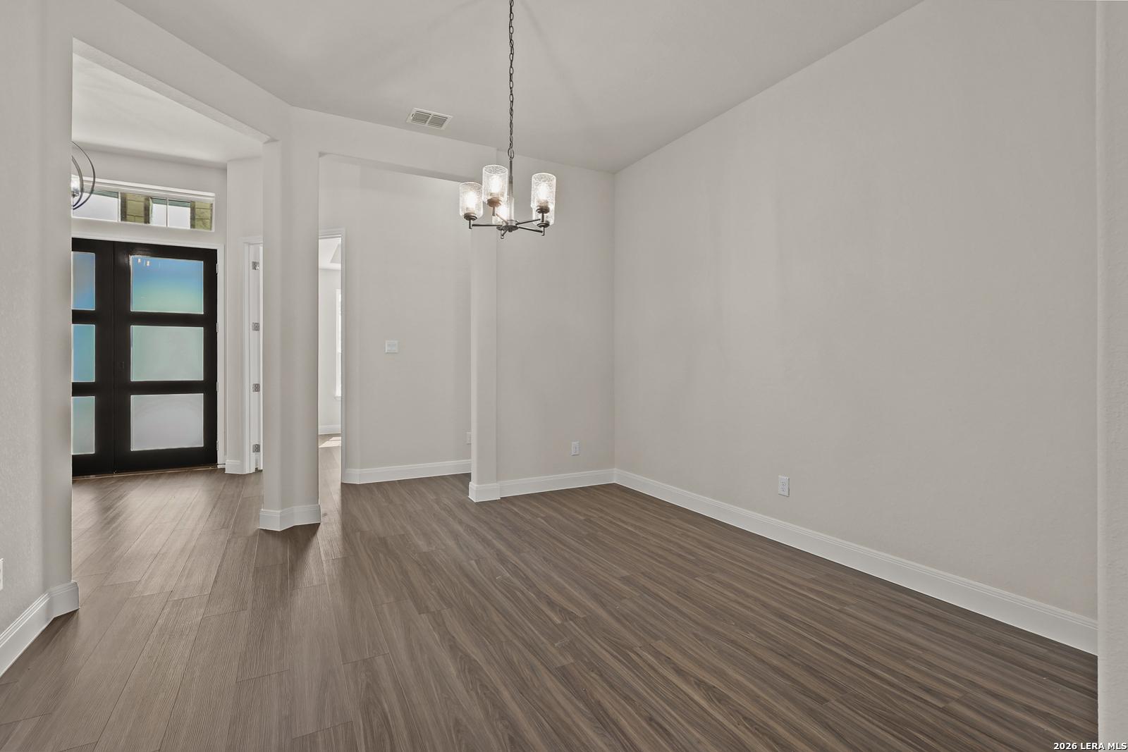 Elegant dining room with modern chandelier and wood-look flooring in The Summerlin B floor plan, Potranco Oaks, Castroville.
